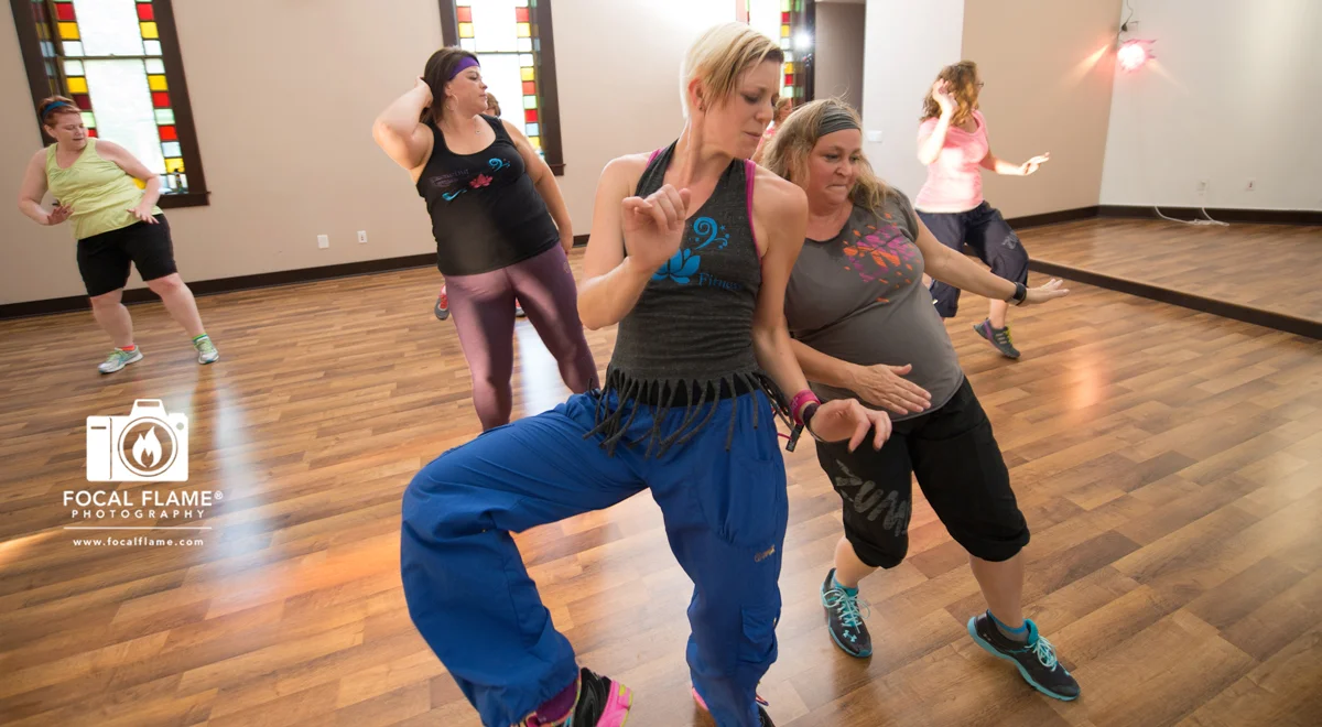 Dancing Lotus Fitness Zumba sessions are full of vitality. The studio is housed in a former church; stained glass and high ceilings add to the ambiance while instructor Erica Neis (center) leads a high-energy class. © 2014 Focal Flame Photography | Photo credit: Clint Thayer