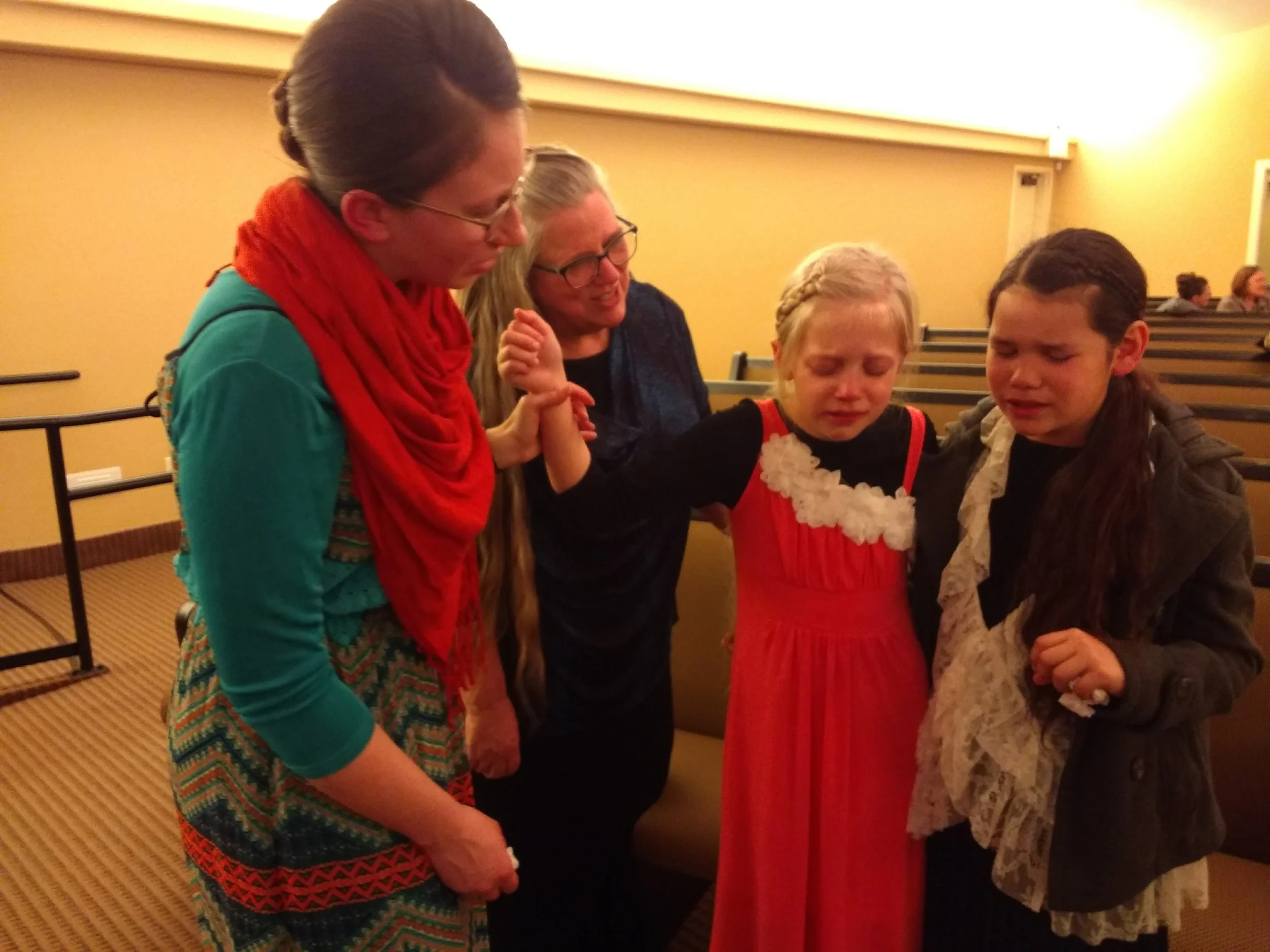 Emily and Jaz praying together with mom Jen and Grandma Kathryn