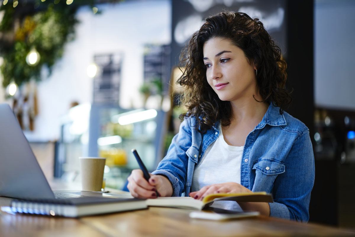 High school student brainstorms a Common App Essay topic while working on a laptop at a coffee shop