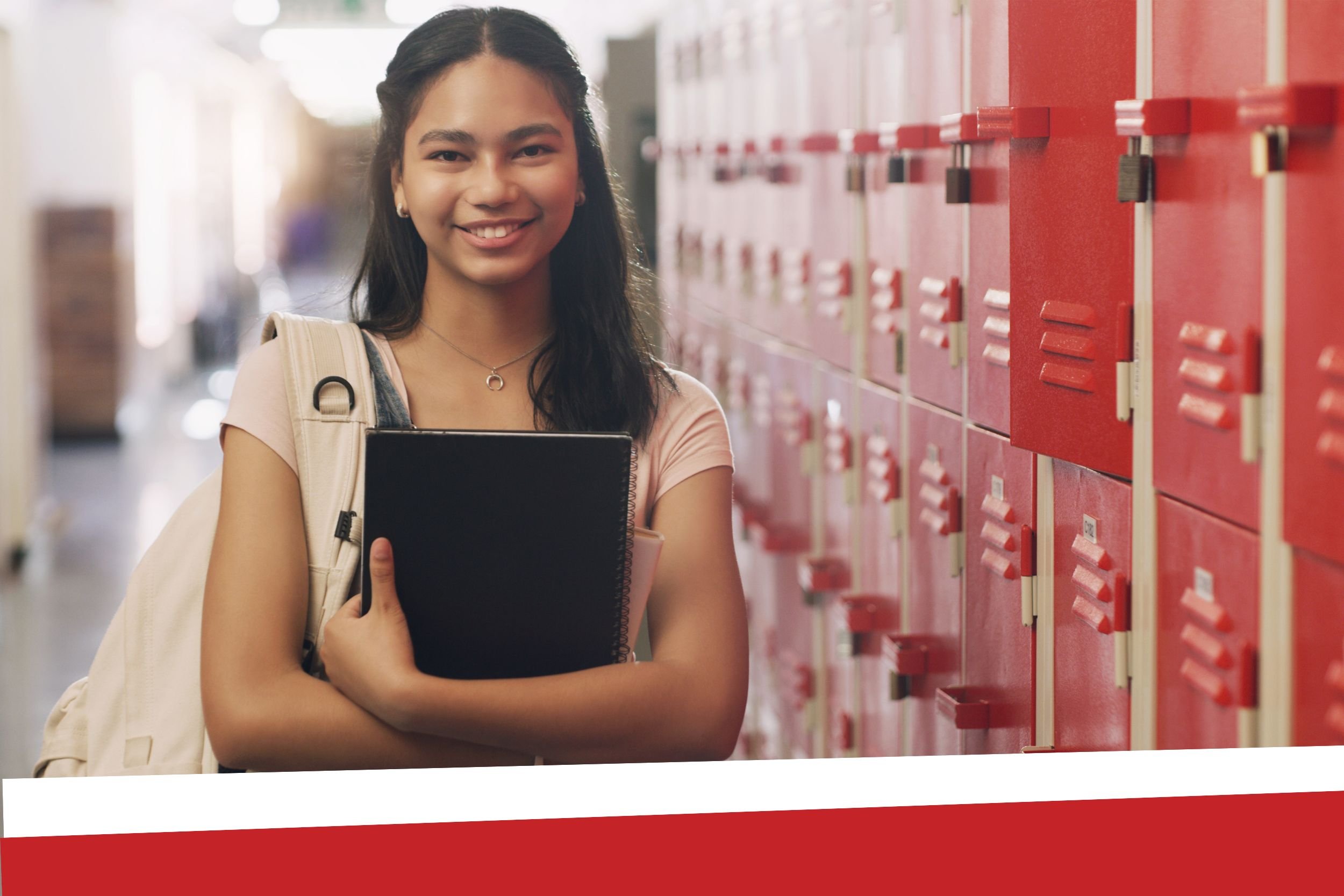 High School student holding book in front of lockers.