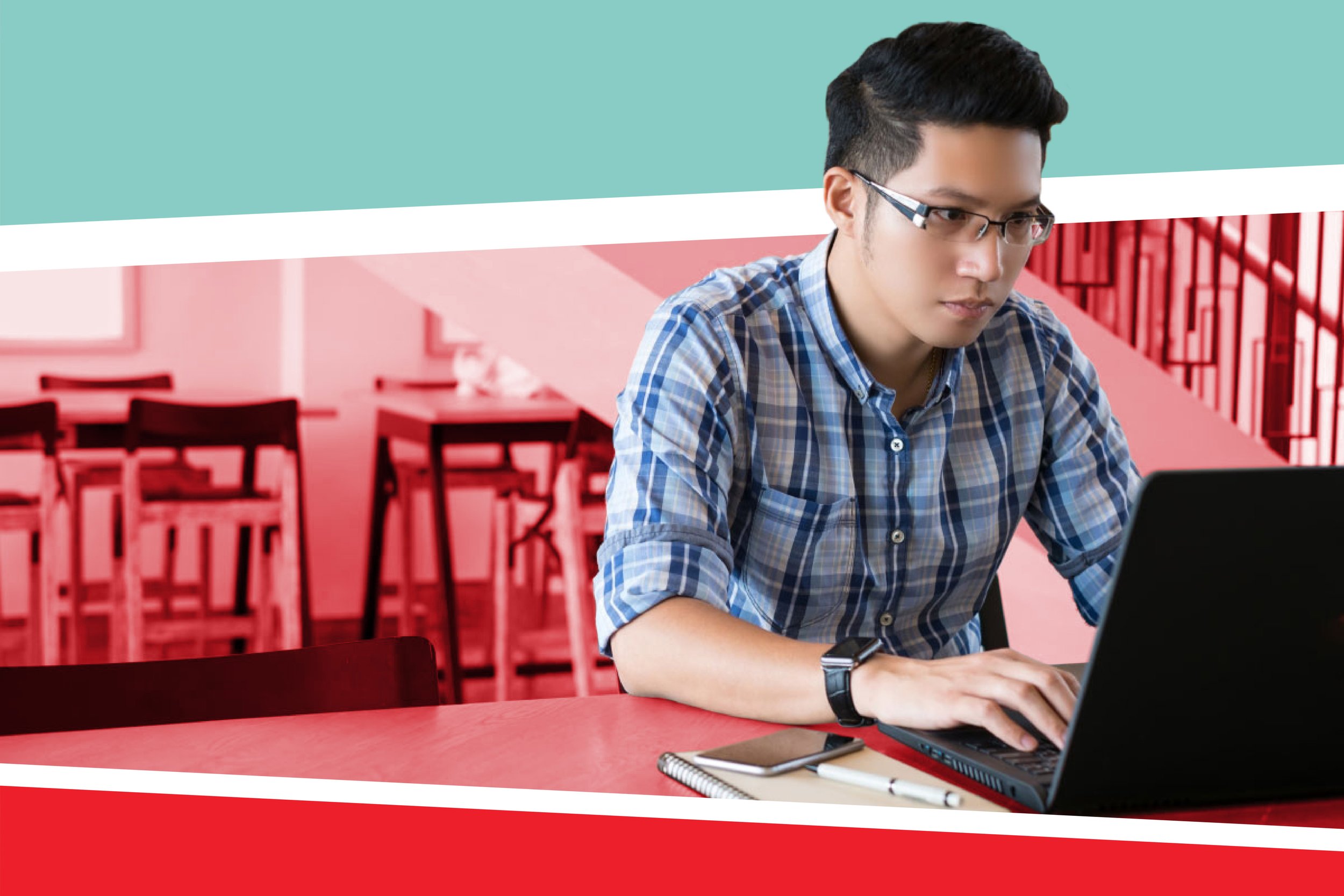 student wearing blue plaid shirt and glasses using a laptop in the library