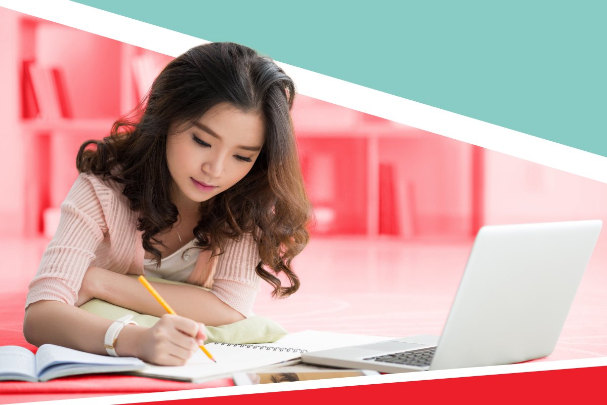 a student writing a common app essay using a laptop and notebook in a library