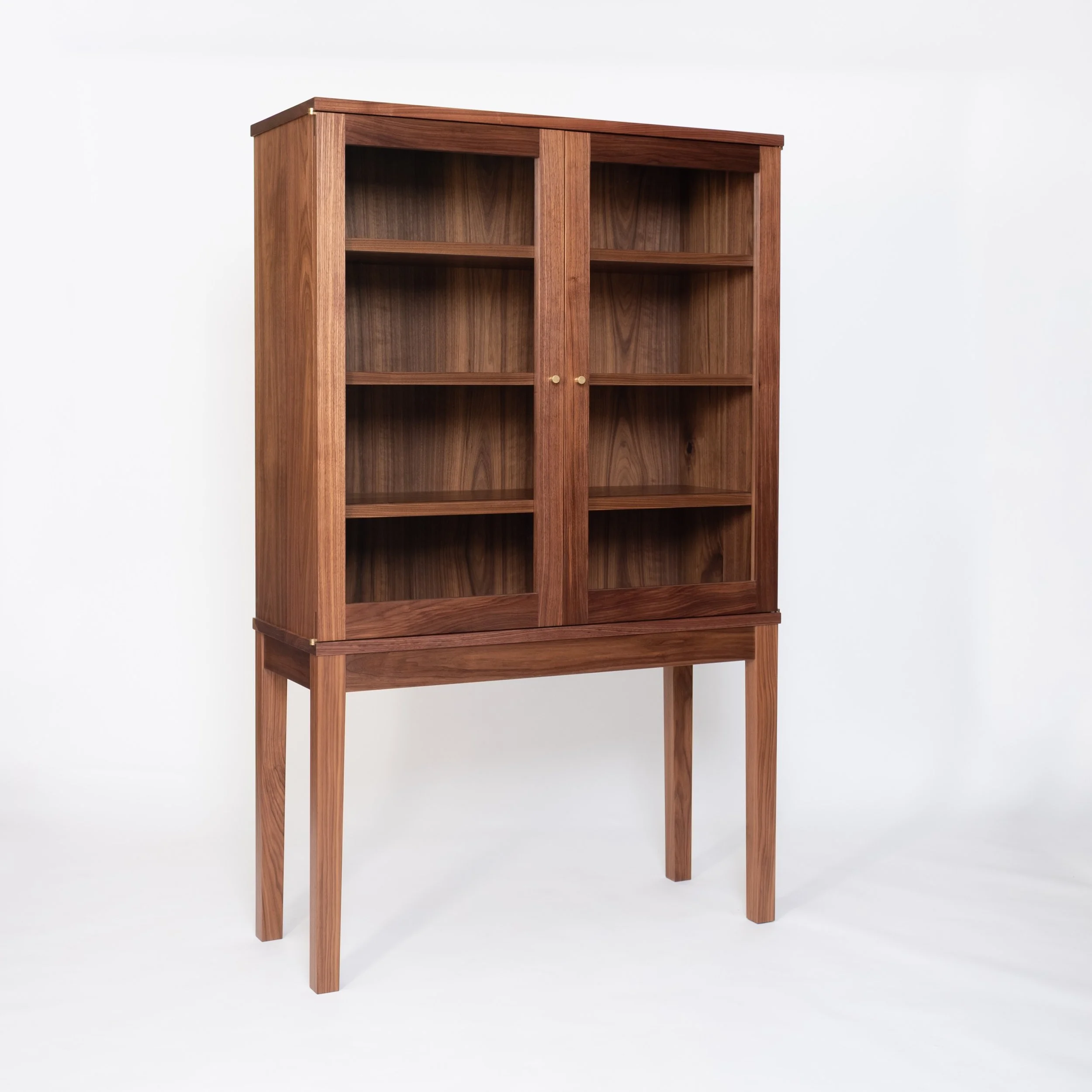 Custom dish cabinet in walnut with glass doors, brass hardware, and integrated lighting!