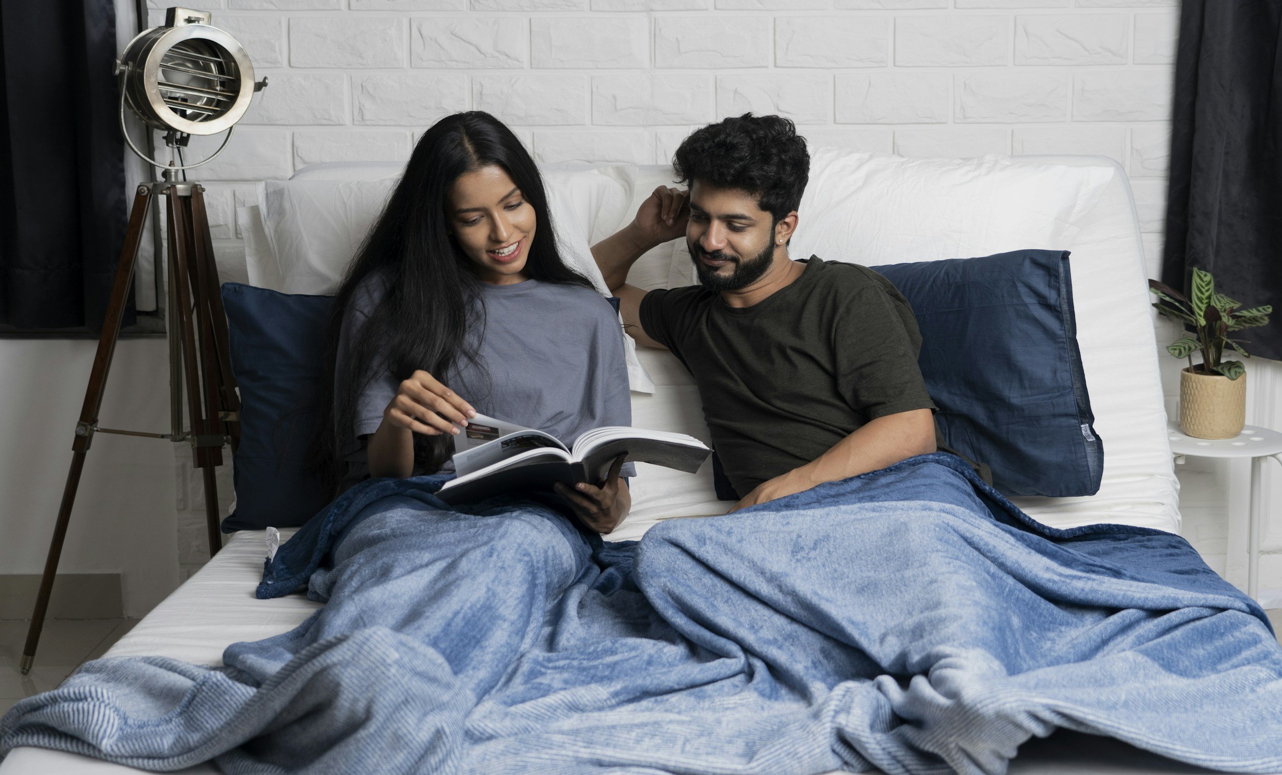 Couple in bed looking at a book together