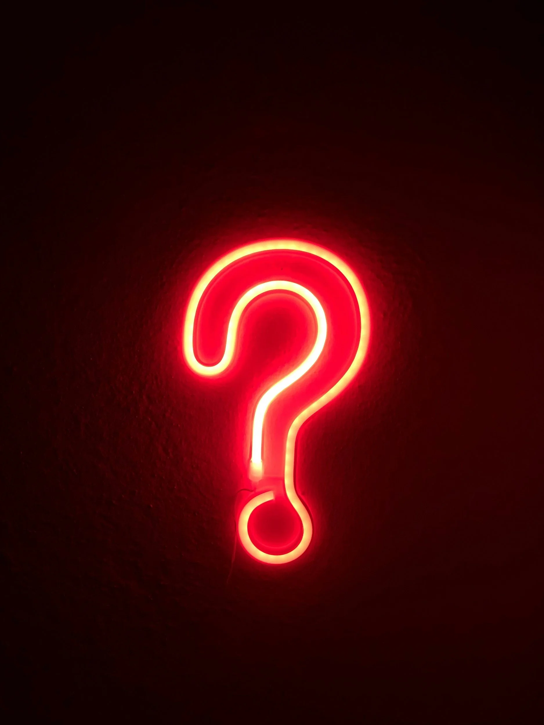 orange neon question mark lit up on a wall