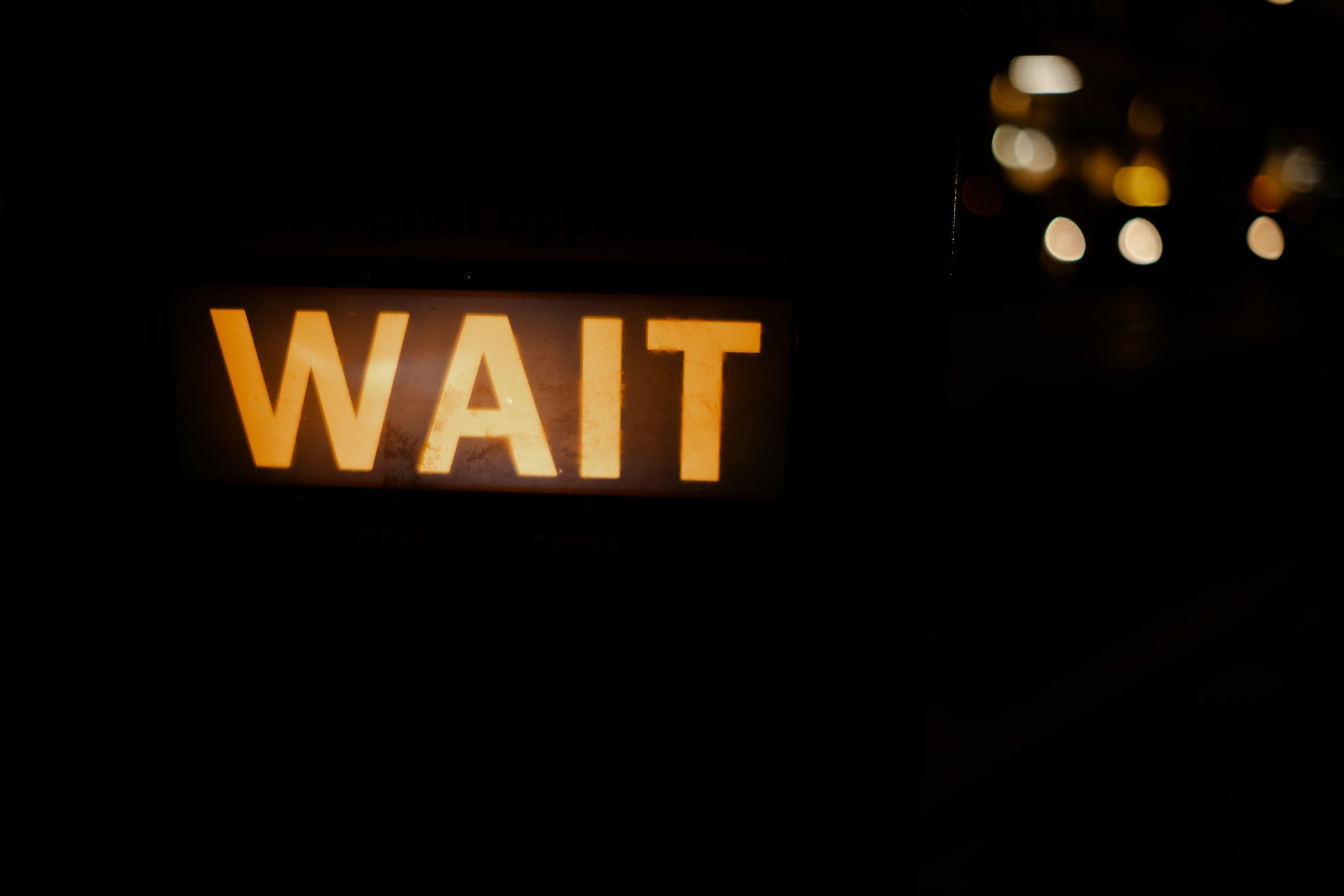 gold "wait" sign lit up against black background