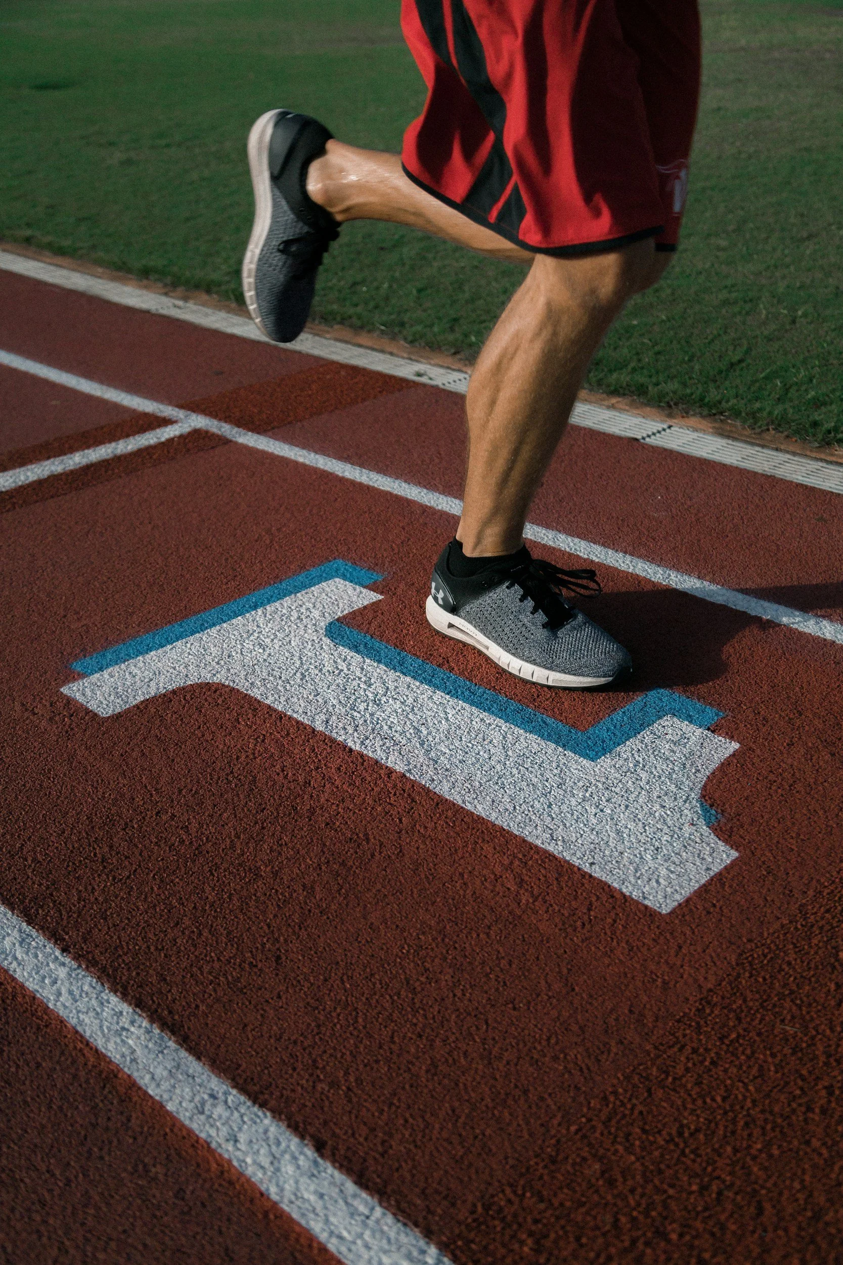 man 's foot on a track stepping next to the number 1 painted on the track