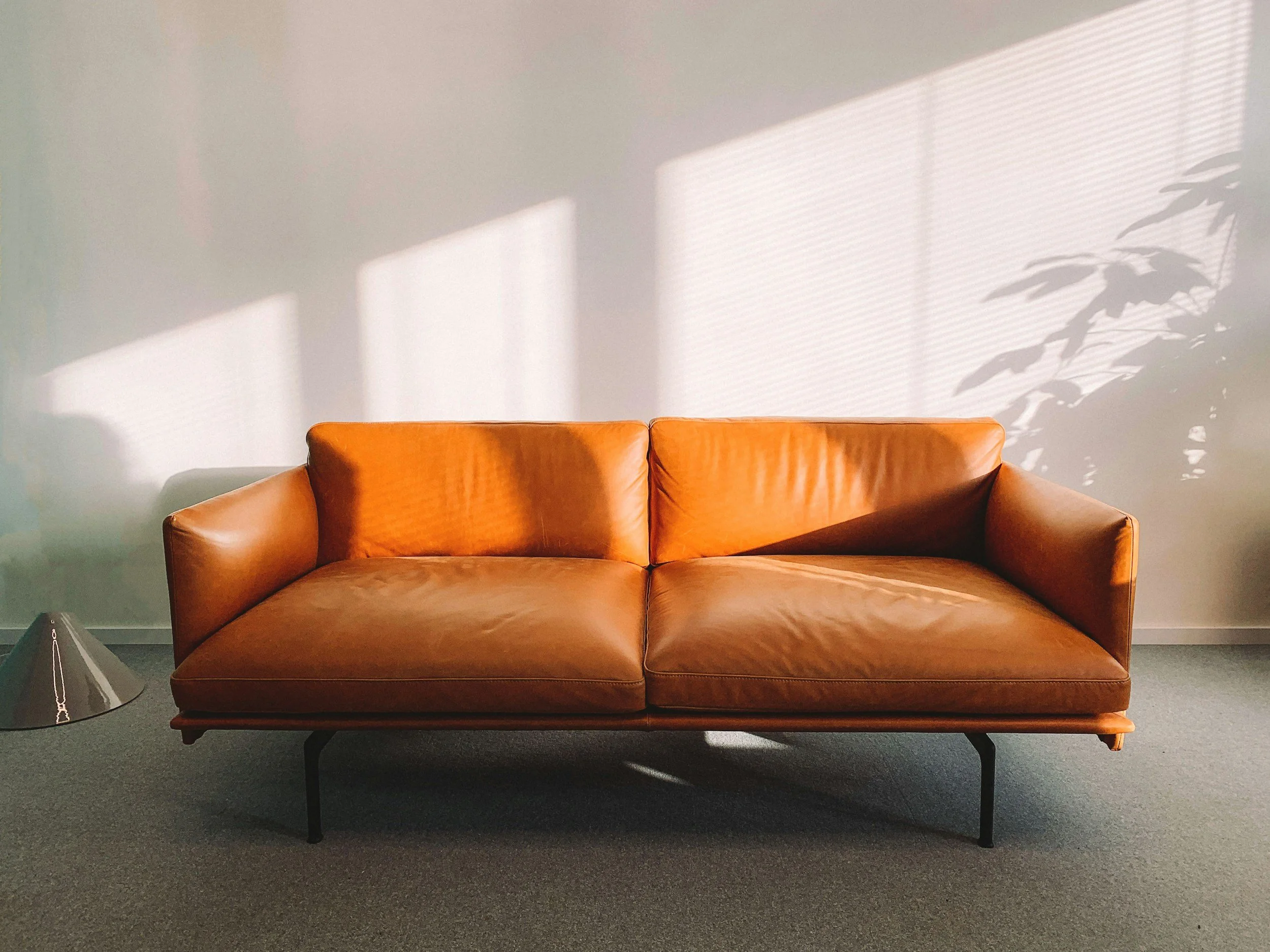 brown leather mid-century modern style couch against a white wall