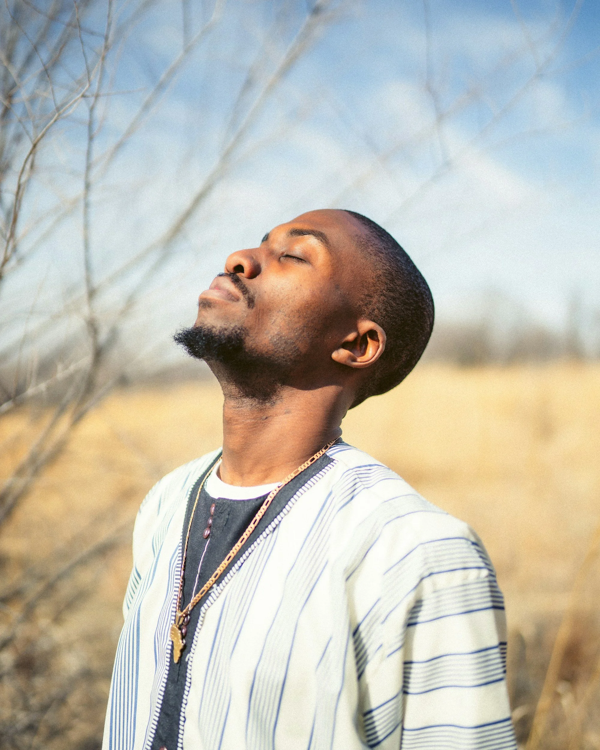 African man with his eyes closed looking up at the sky signifying staying with the process of a trauma healing intensive