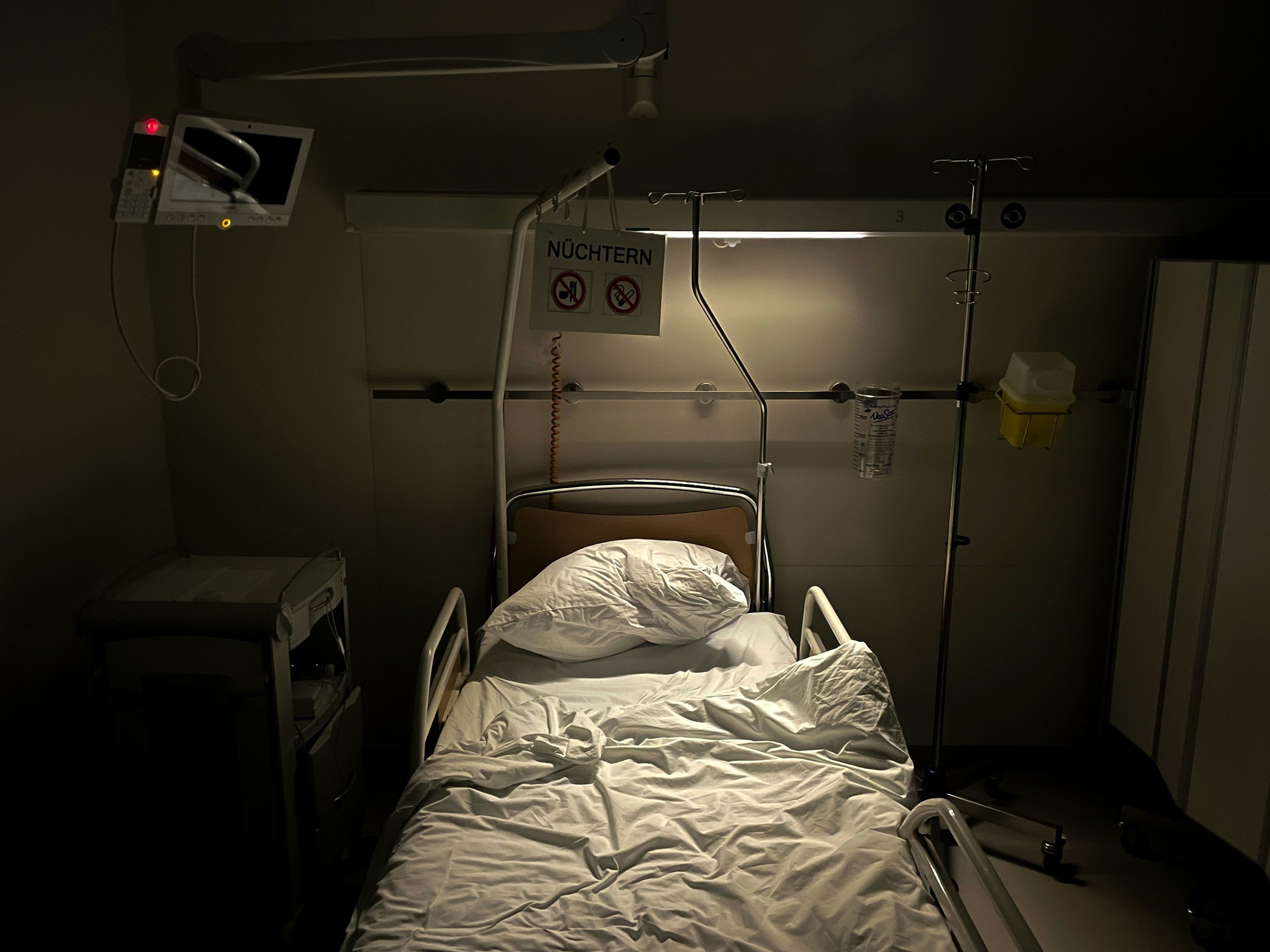 empty hospital bed in a dark room with light above it to depict the hospital bed in the story