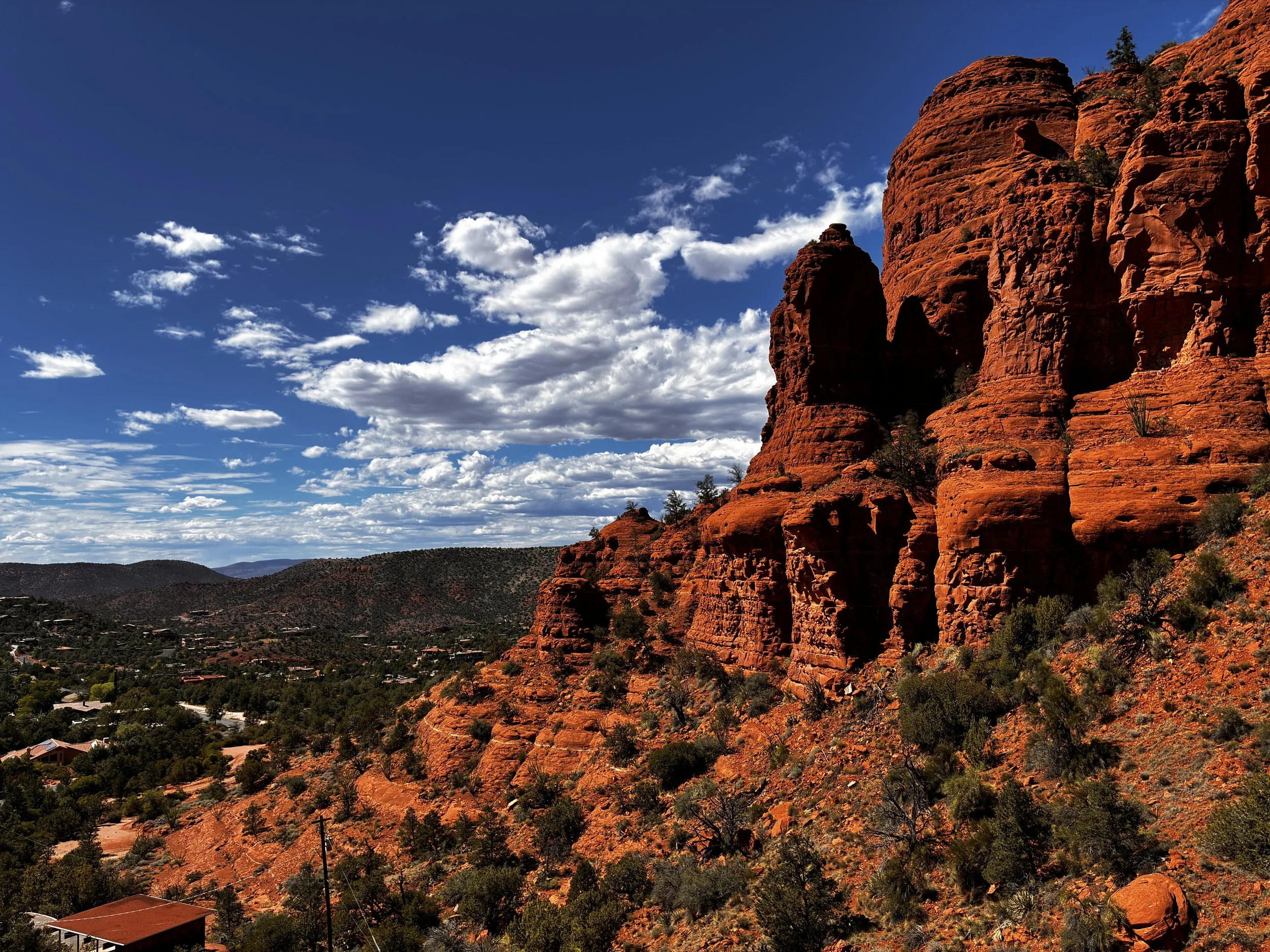 Image of a red rock formation in Sedona, Arizona against a blue sky with clouds signifying the breath work retreat I went to