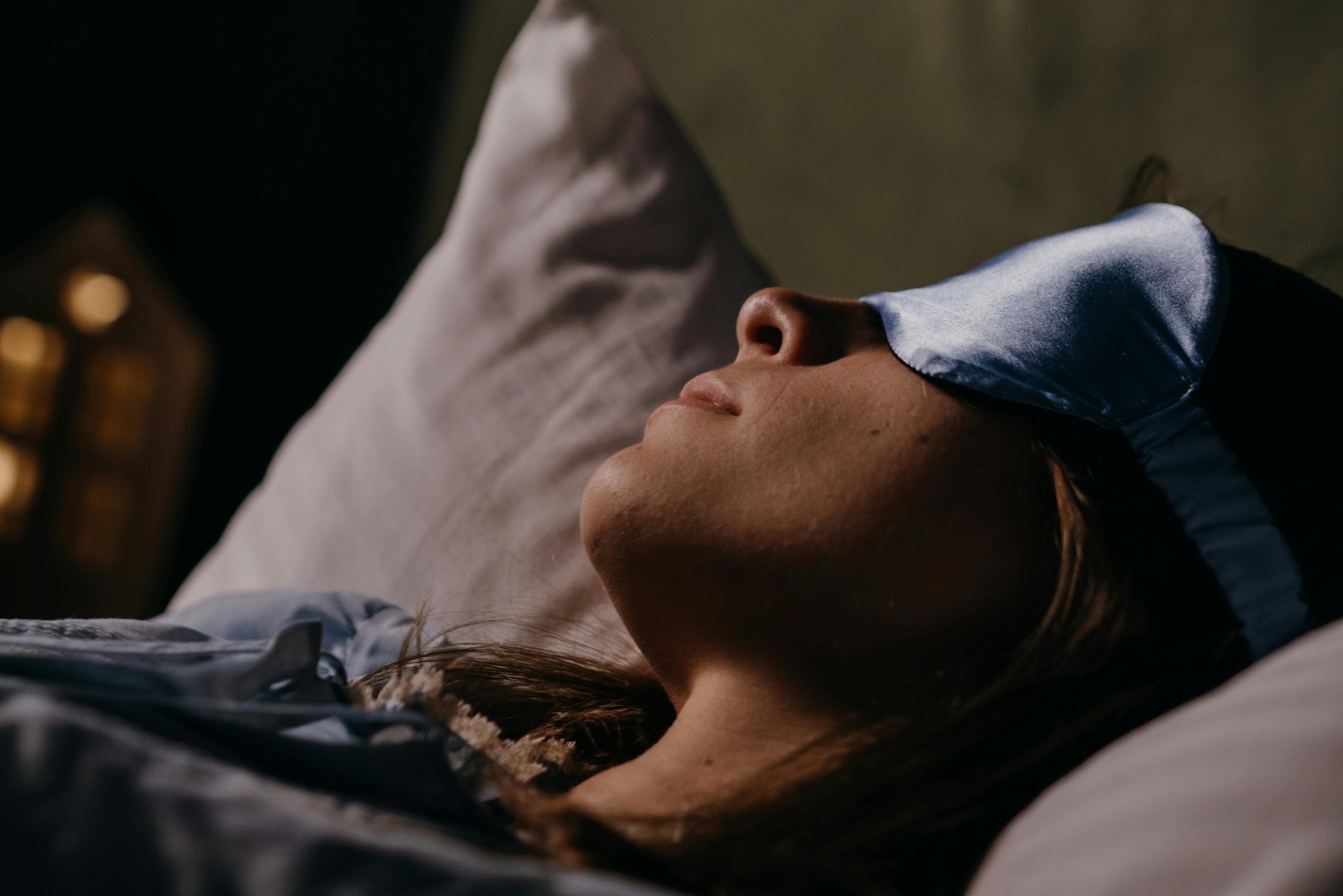 a woman wearing an eye mask is laying down, symboiic of the process of ketamine assisted therapy for trauma
