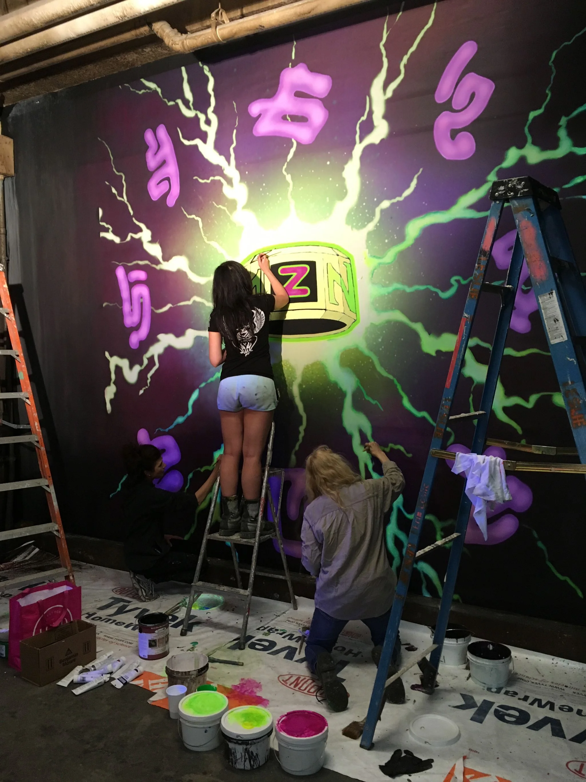 Artist Aurora Kruk works on a mural celebrating the Z-Band, the device that restored the zombie's humanity. 