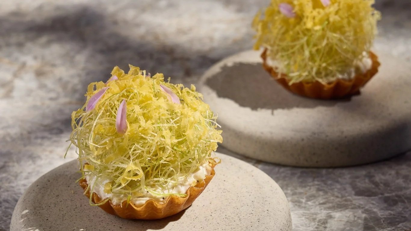 Tartlet topped with fried leeks and garlic flowers