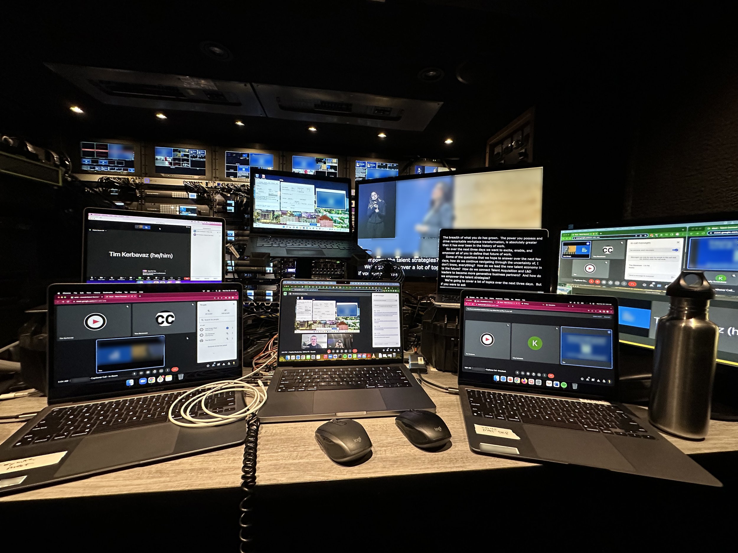 Broadcast production truck interior with multiple laptops and monitors running live captioning and video feeds.