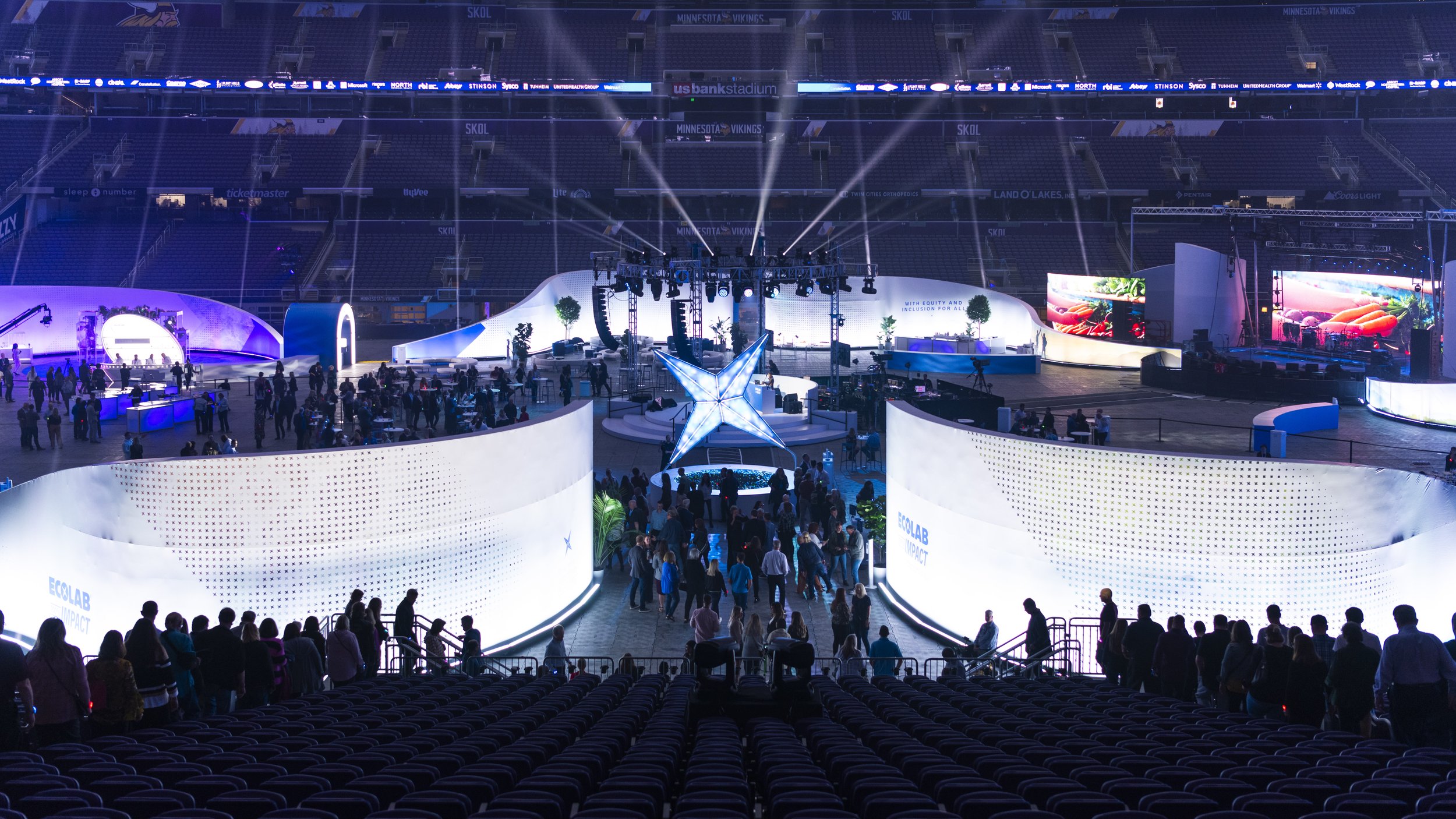 A large-scale corporate event that Talon AV supported in an arena at US Bank Stadium, with large curved scenic panels, dramatic lighting, and eye catching networked activations.