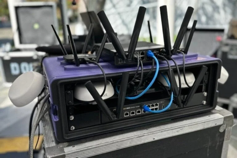 A router in a purple rack with multiple antennas stacked on top.