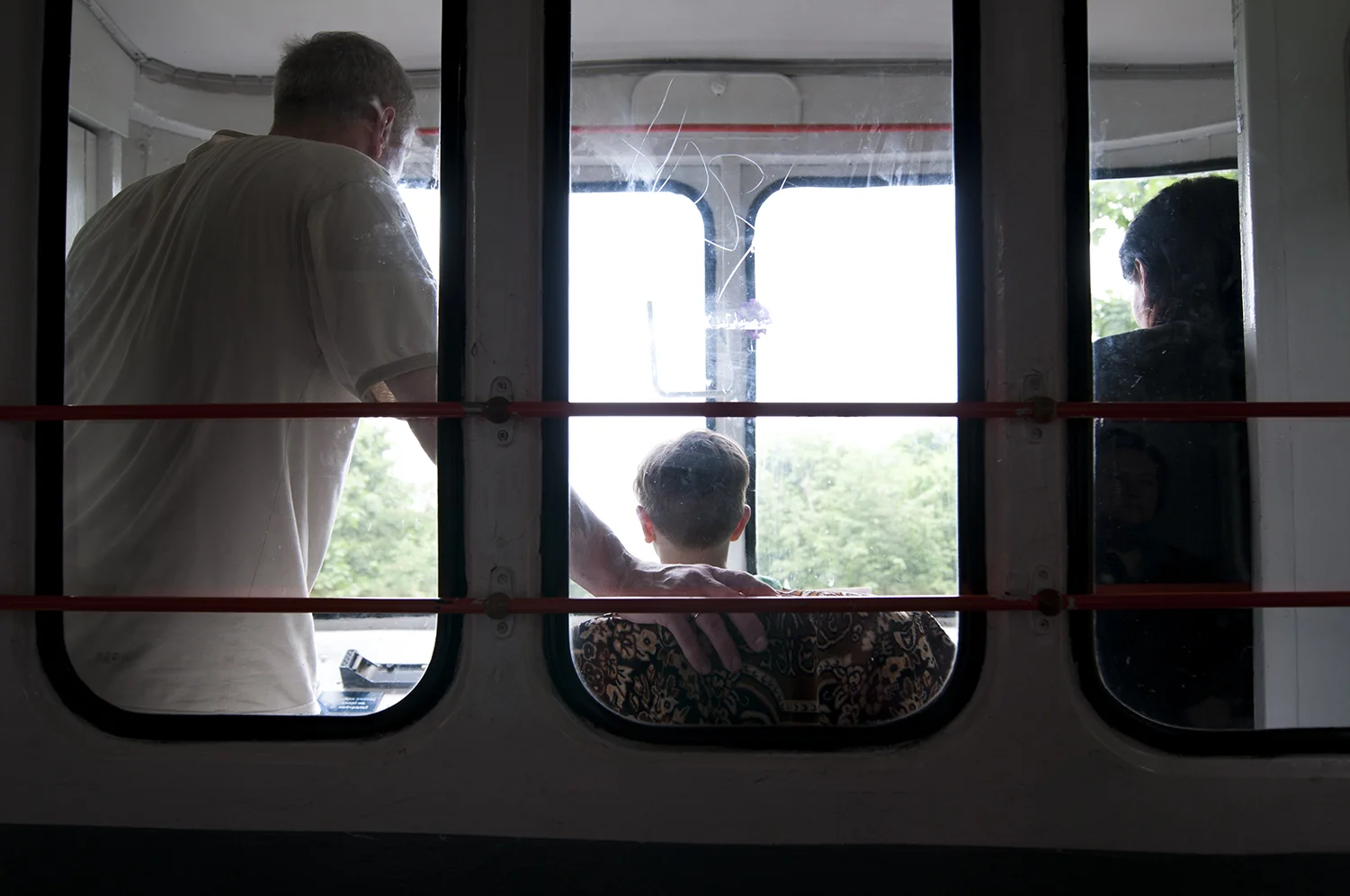 Young child sitting behind the commands of the funicular under the supervision of his father and the driver