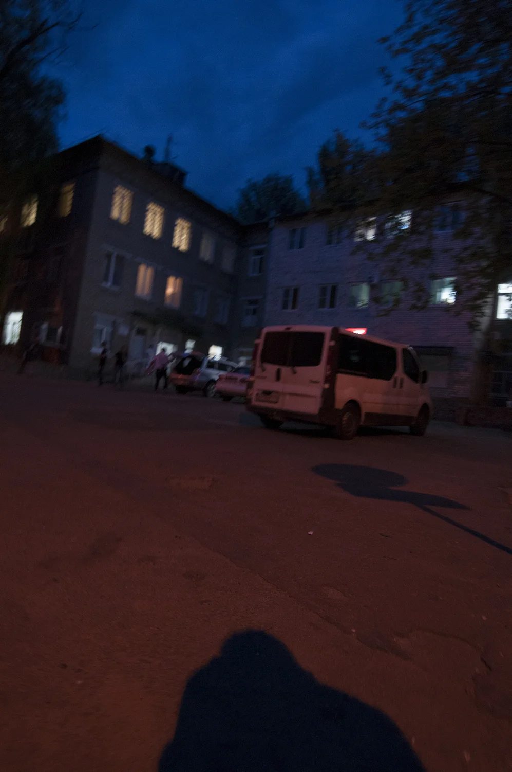 A man armed with a automatic weapon closing the trunk of his SUV while two other people watch over the people present in front of the downtown hospital's trauma unit, Donetsk.
