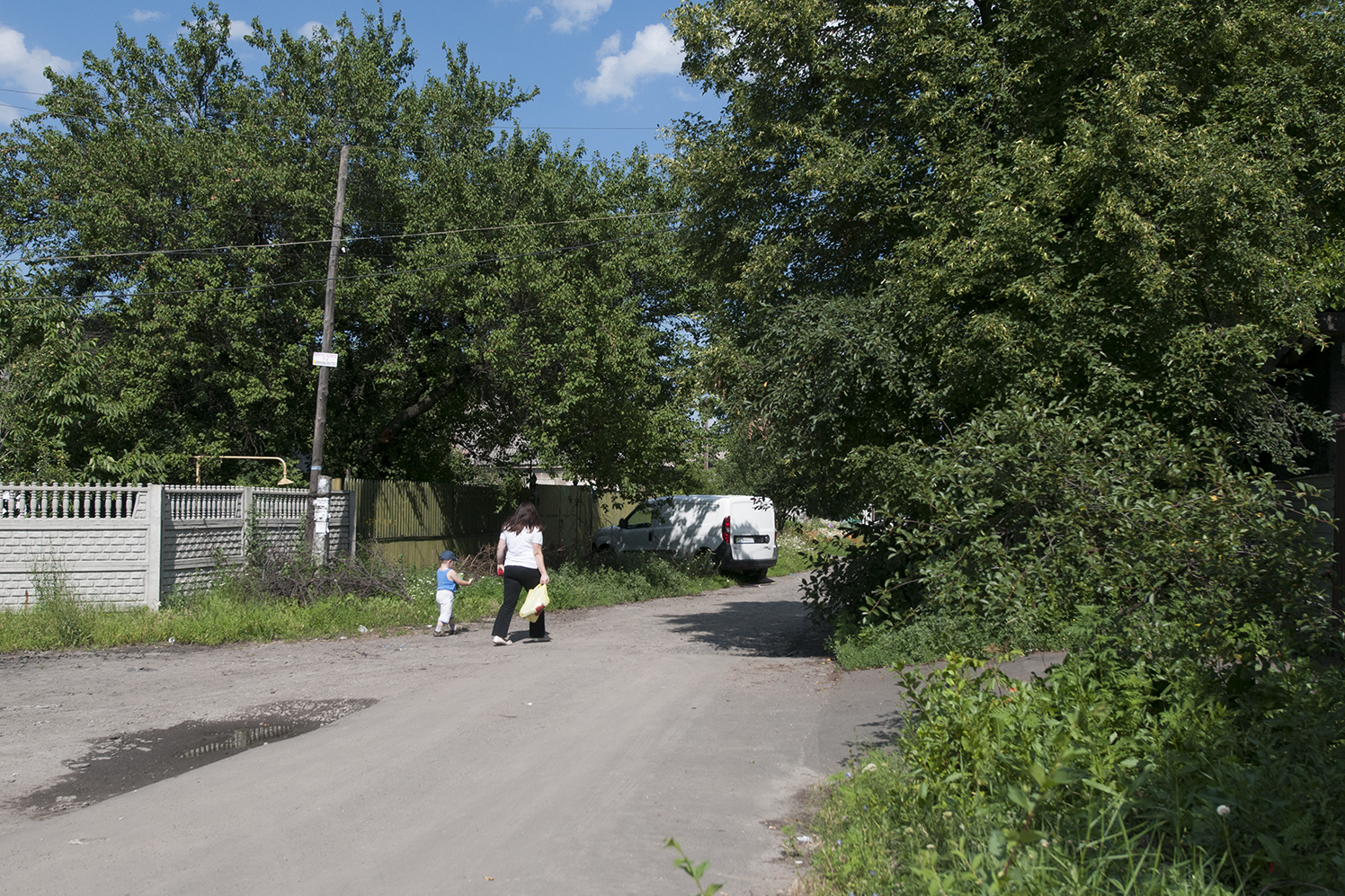 Woman carrying a bag of groceries with a young child walking next to her