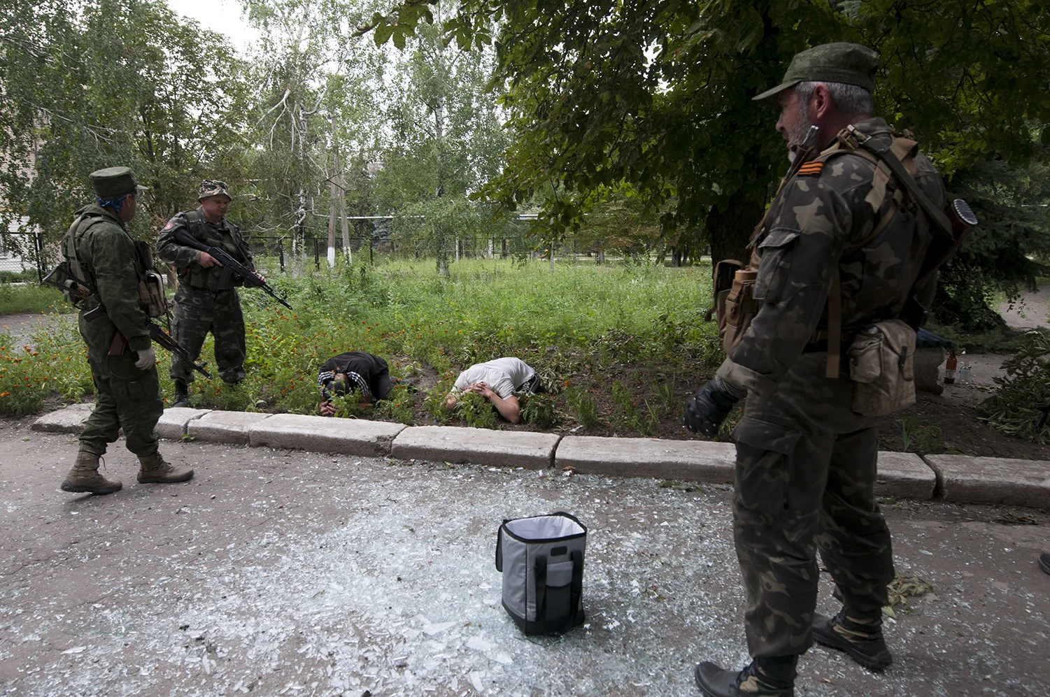 As the bag of looted goods lies in the middle of scattered pieces of glass, the two men are putting their faces against the ground after the soldiers shouted at them to do so, one of them received a kick to the ribs in the process.