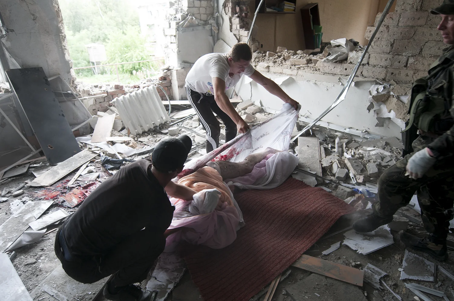 The looters struggling to move the body on a rug under the order of the separatists who arested them 