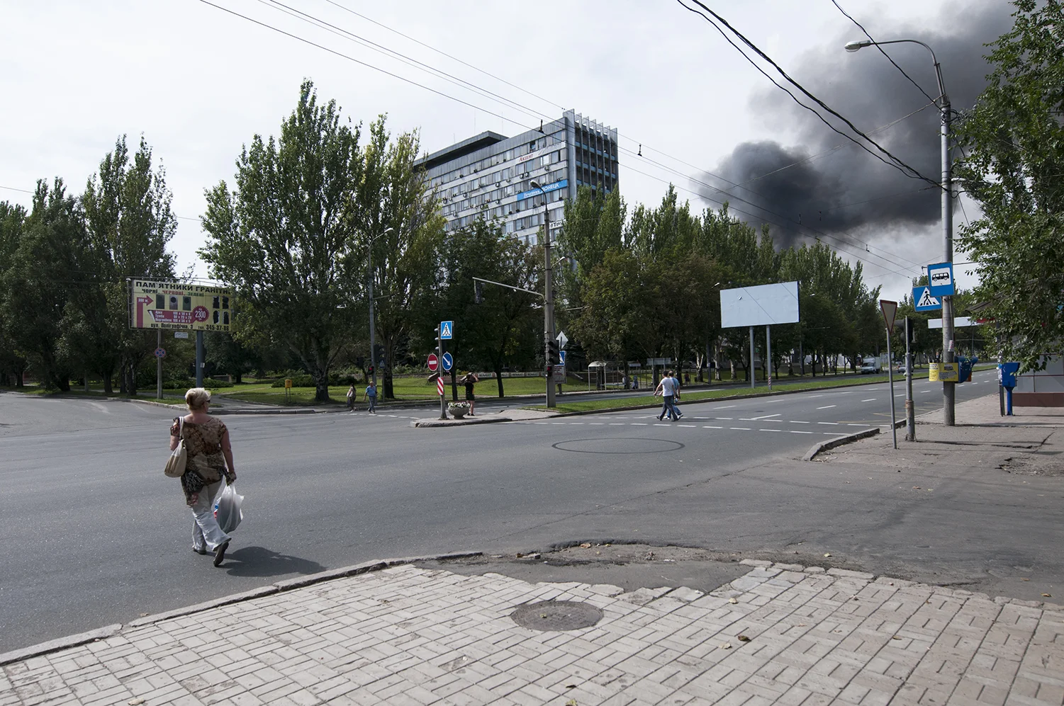 A woman looking at the dark smoke coming from a burning factory