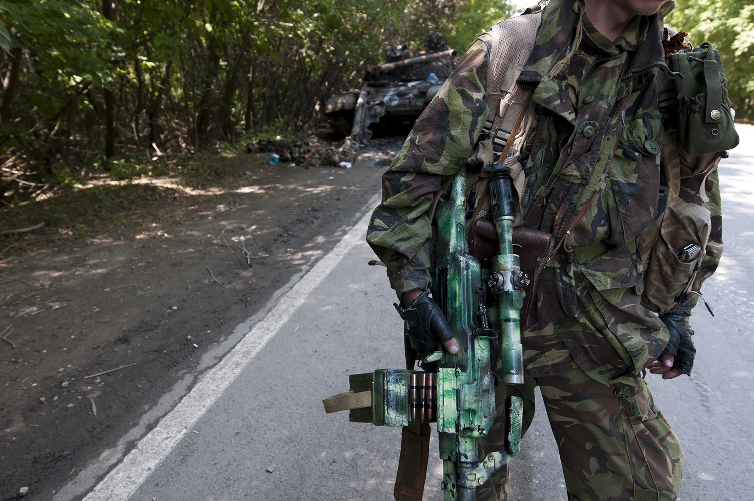 DPR solider standing in front of the deceased tank crew laying on the ground next to their vheicle 
