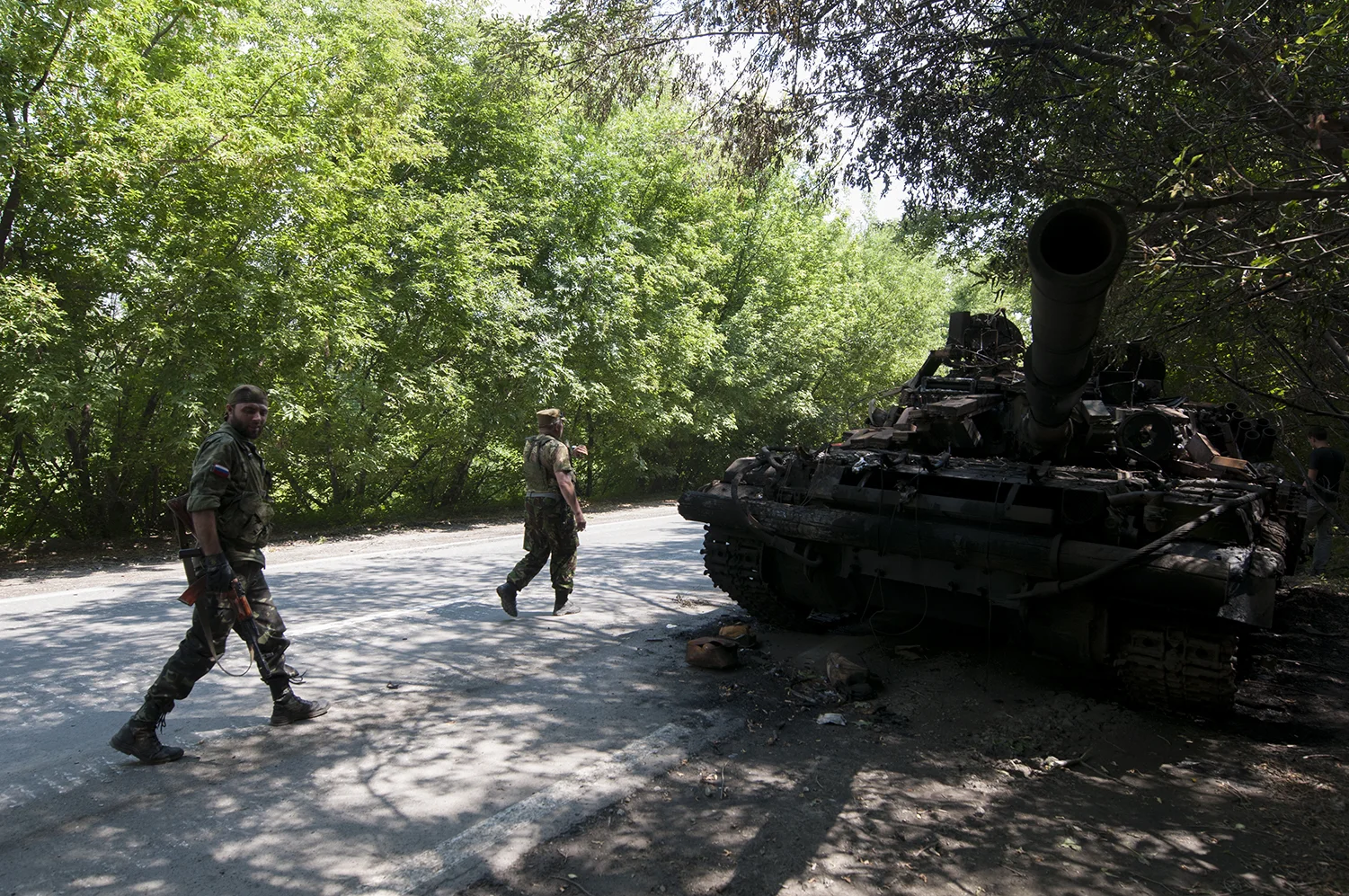 Two separatist soldiers walking past the tank's remains 