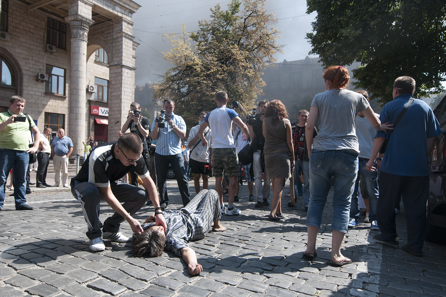 Man checking on a woman that decided to lie on the ground between the protesters and the National Guard after she the first the first that they were all brothers coming from Maidan in order to prevent an escalation of the riot 