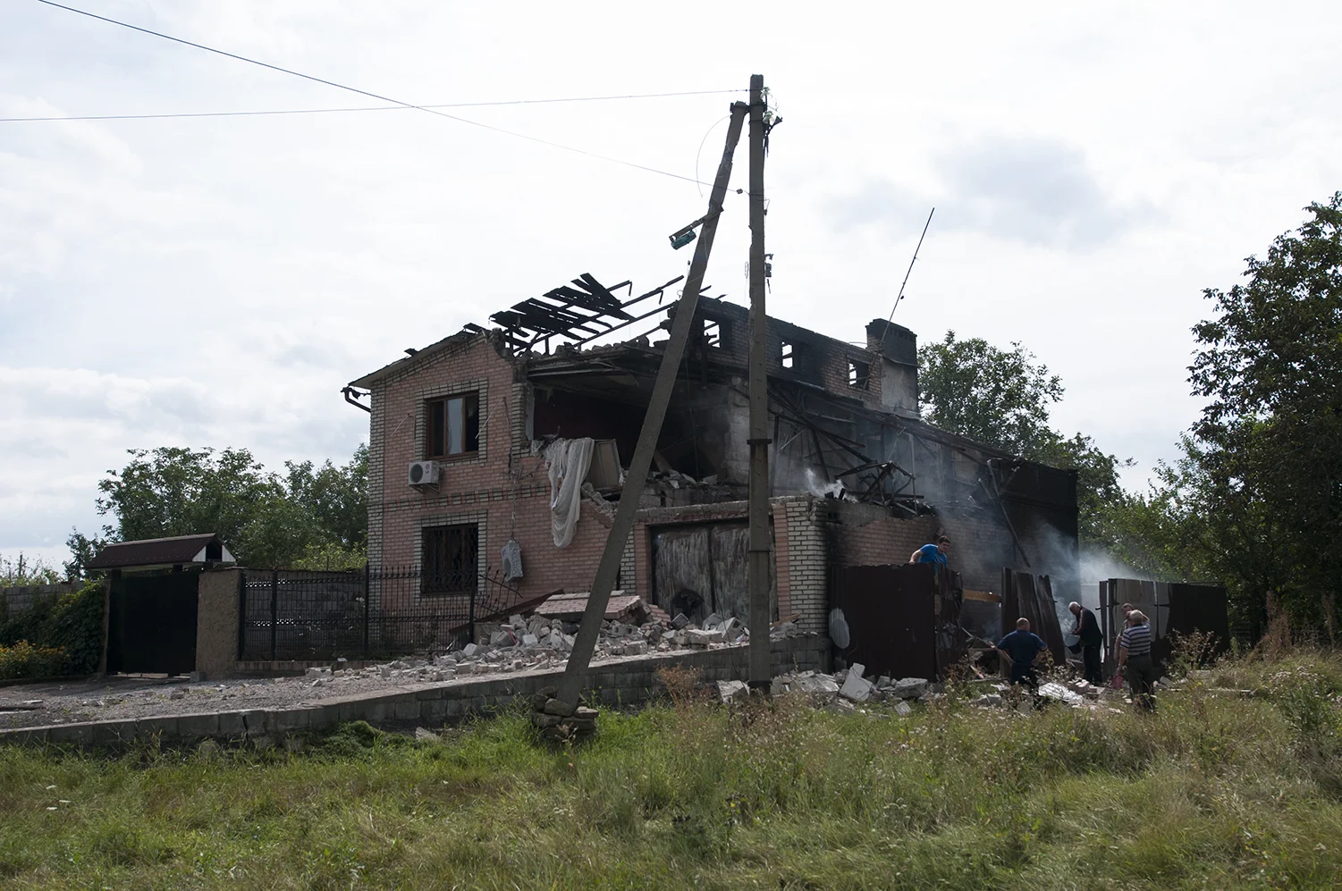 Men pulling out debris out of a house three hours after it got hit by artillery fire. The locals blamed the damages on Putin and reported the presence of a DNR compound nearby