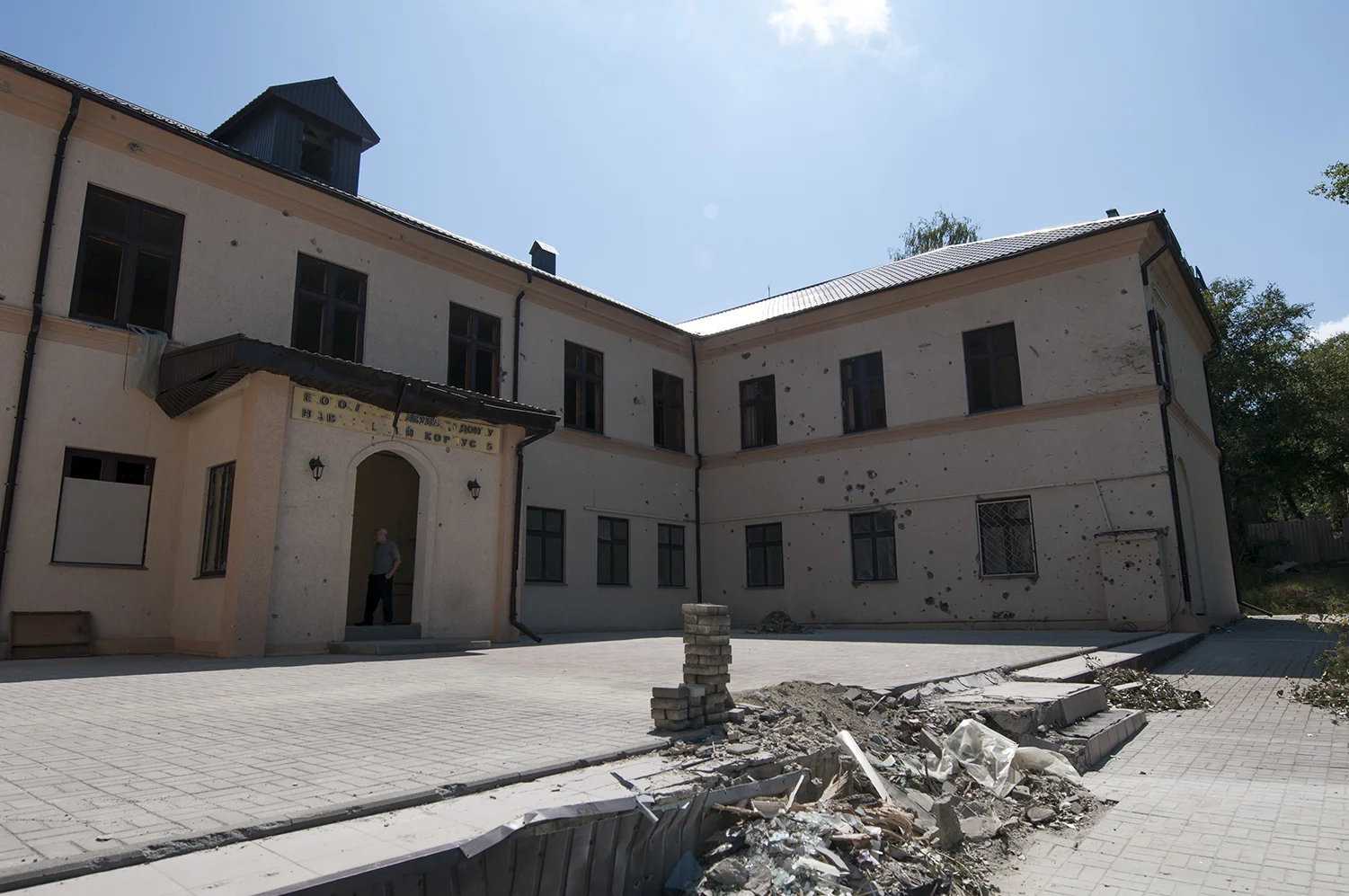 Man standing in the entrance of a damaged school 