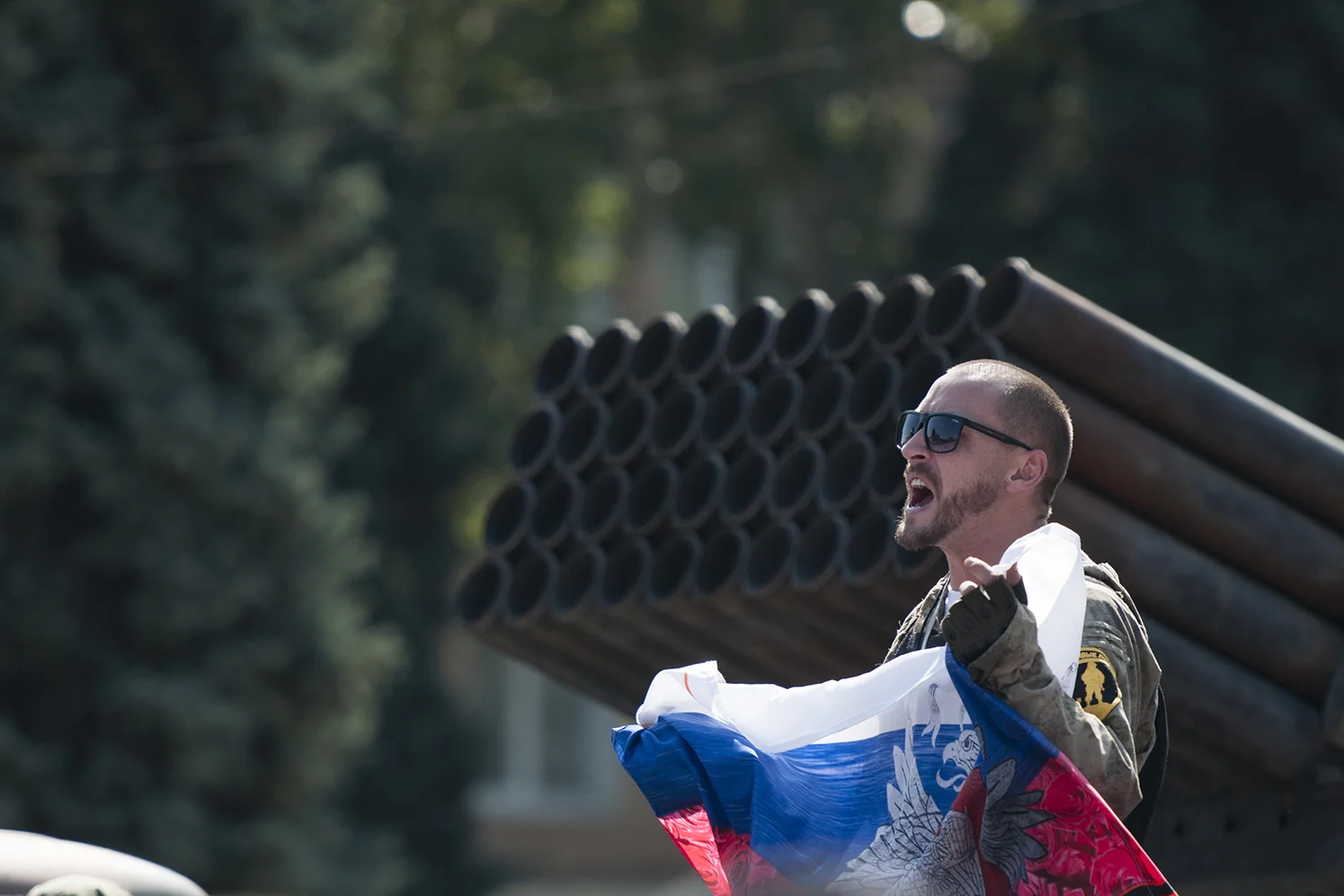 DNR soldier cheering in front of a BM-21 remains 