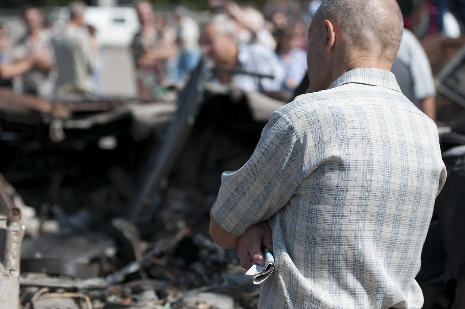 An old man looking over the remains of a UKrainian APC 
