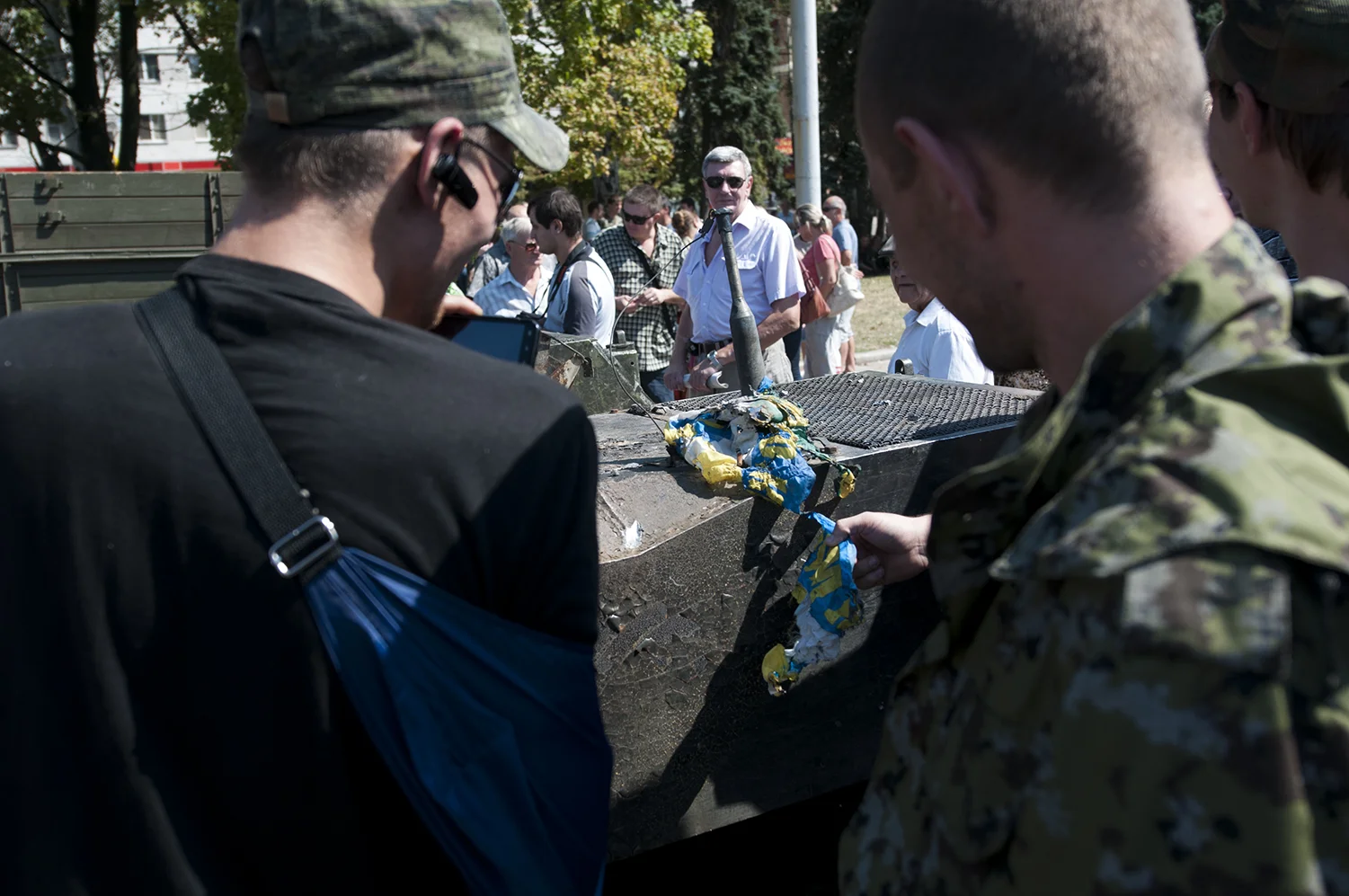 Man looking at three separatists solider who are laughing at the view of burned Ukrainian flag
