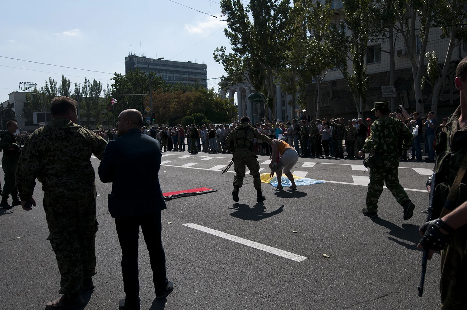 DNR soliders reach for a woman who puts down a Ukrainian flag on the road next to an other one from Pravy Sektor