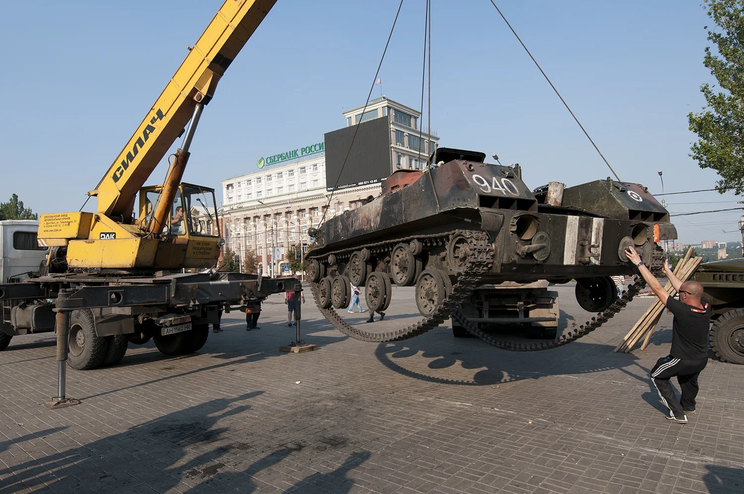 A man pulling onto a destroyed Ukrainian APC 