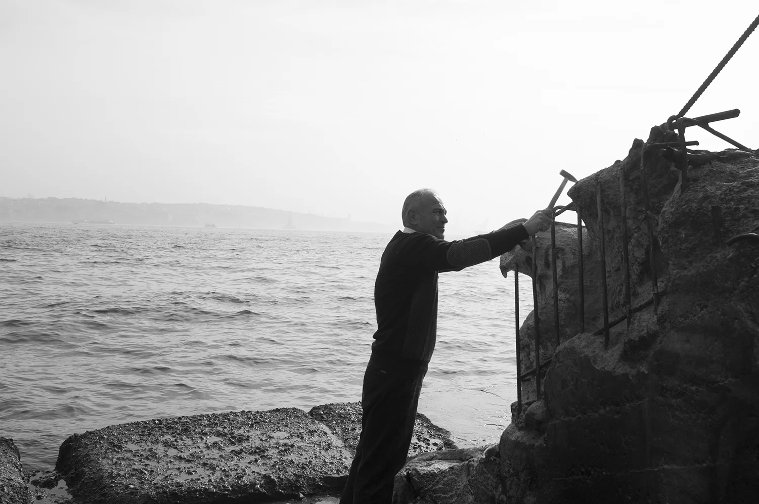 Artist sculpting an eagle in a reinforced concrete block on the Bosphorus strait side.