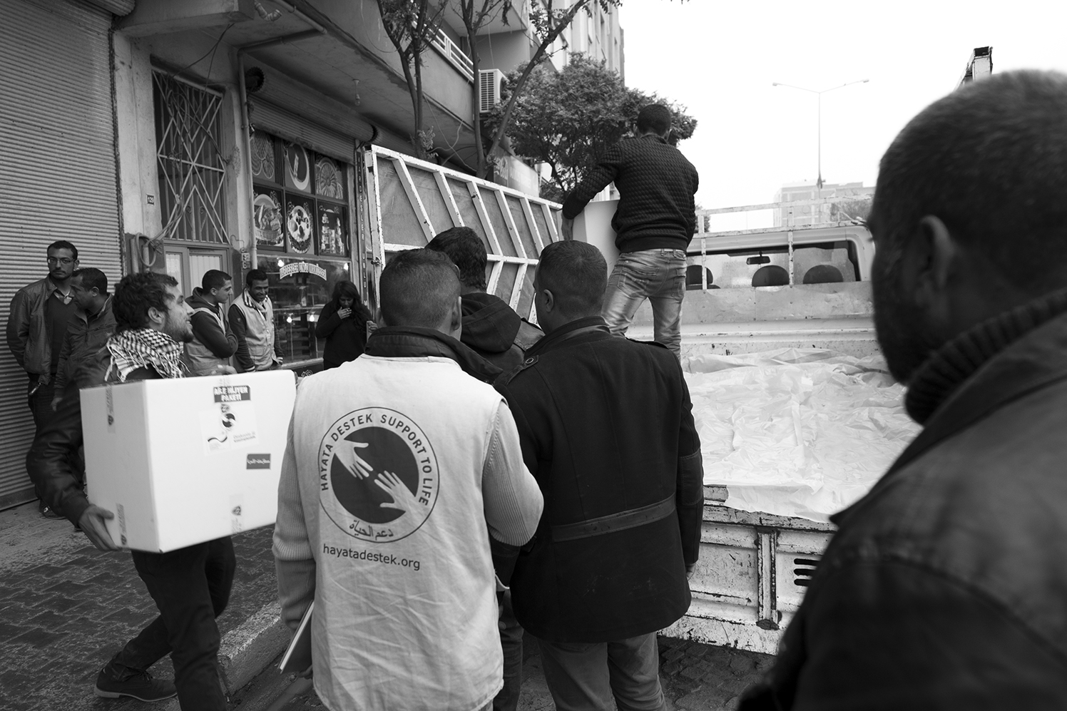 Volunteers and Hayata Destek workers loading relief package in the back of a truck in the center of Suruç. The boxes contain kitchen wear and hygiene products. 