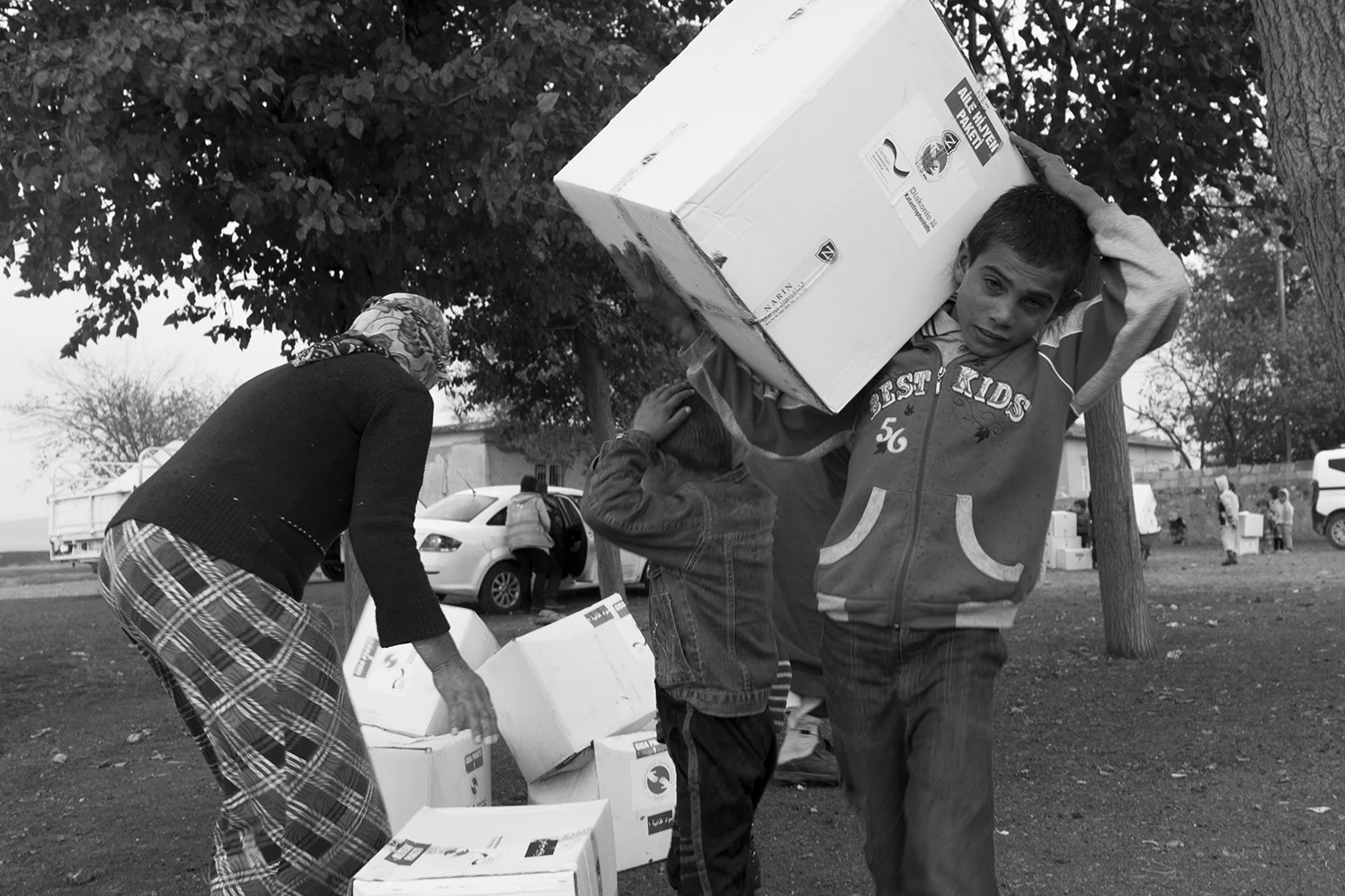 Young Syrian boys helping their mother to bring back the relief package to their tent.