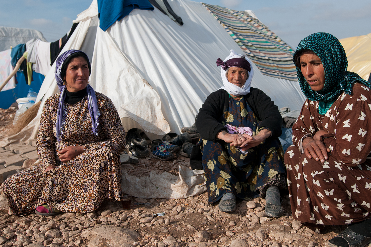 Syrian women sitting in front of their tent in a refugee camp near suruç