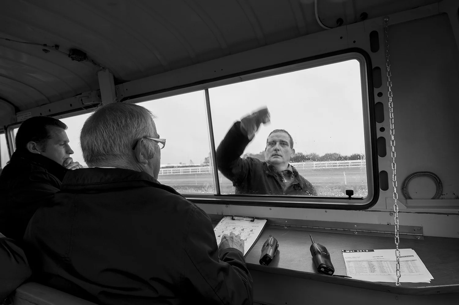 Race stewards sitting in their van as one of their colleague wipe the windows of the vehicle at the end of a race.