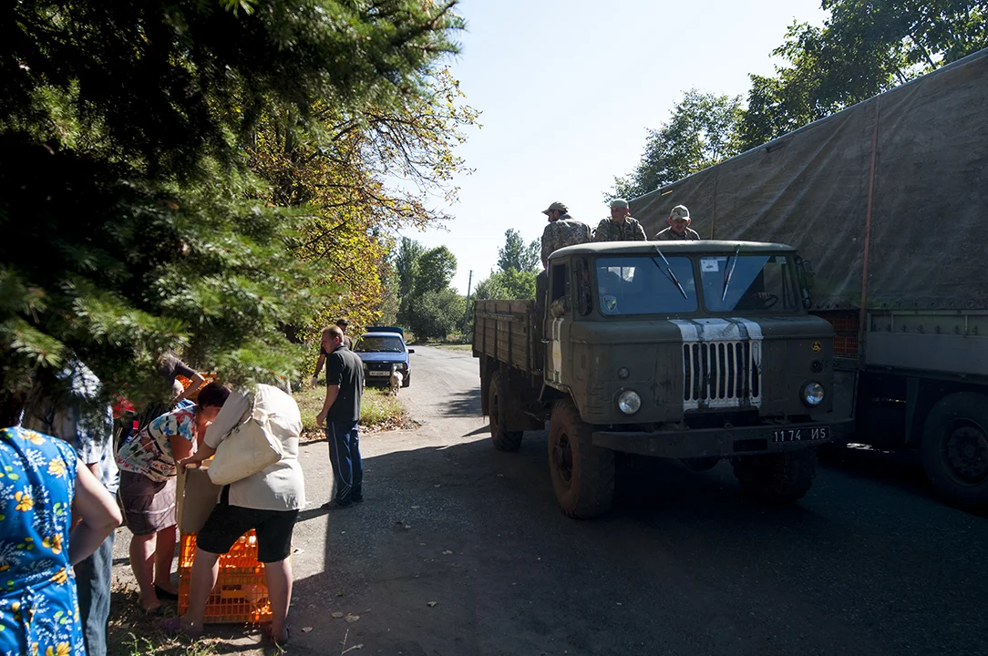 Ukrainian soldiers ridding on a millitary truck as villagers collect their chickens in Klynove