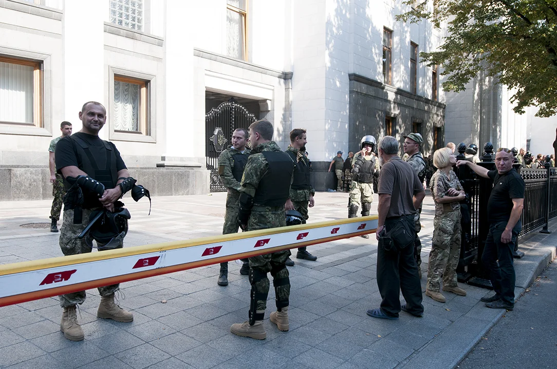 Members of the National Guard smiling as an old man yell at them in from of the Rada an hour and a half aft er the explosion that killed three and injured over 90. 