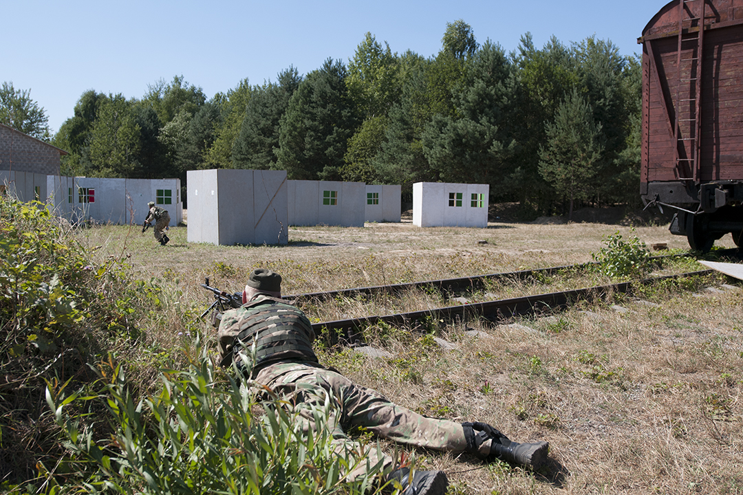 Ukrainian soldier covering his brother in arms during an exercise where they take assault on a fake village hold by their American counterparts.