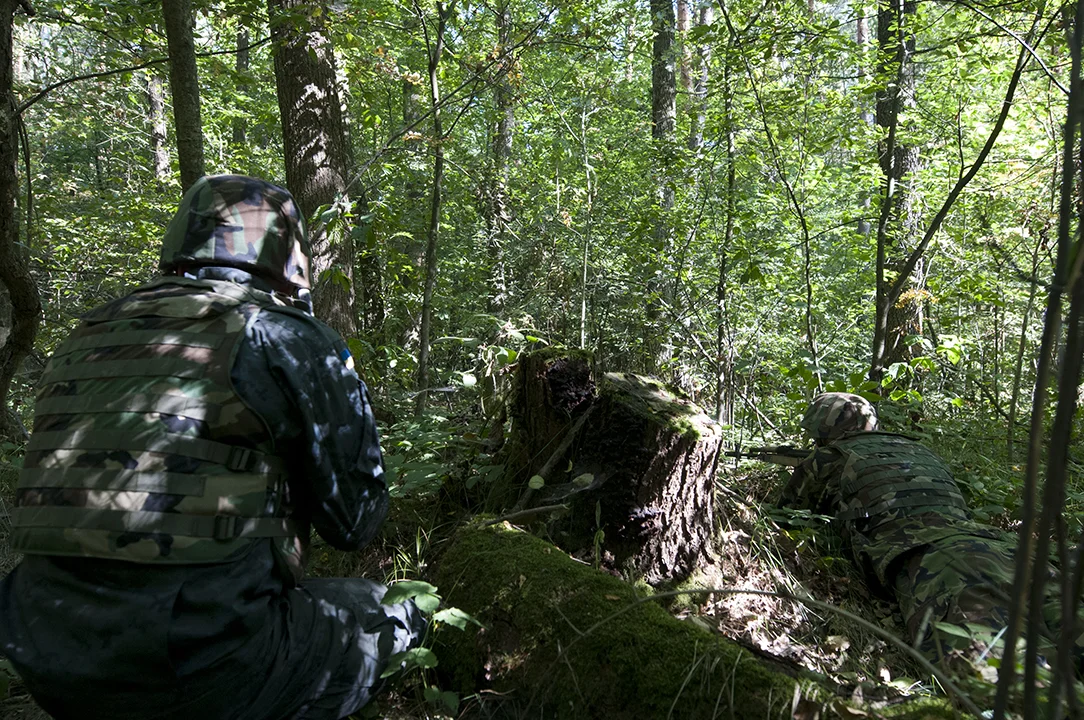 Ukrainian soldiers returning fire from behind cover as they slowly progress inside the forest.