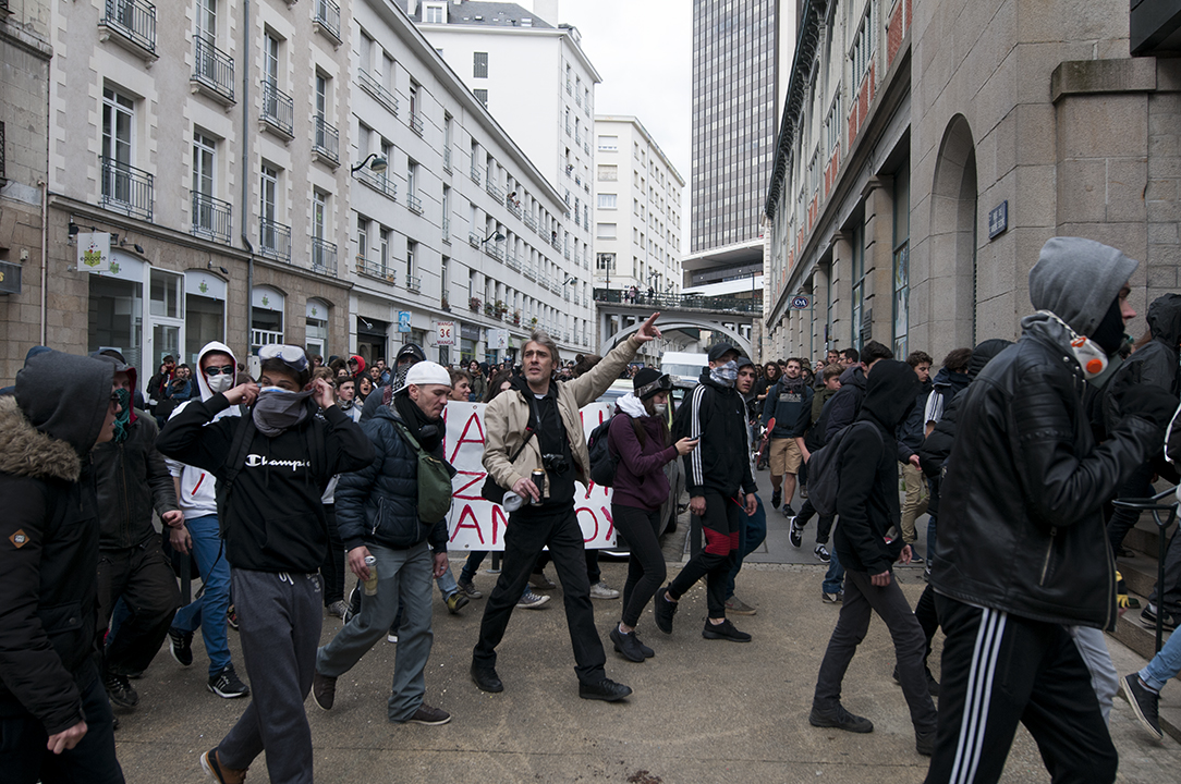 Middle-aged protesters walking alongside masked teenagers.