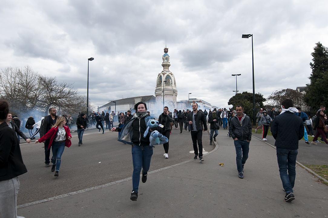Teenager running away from tear gas with a stuffed Stitch under her arm.