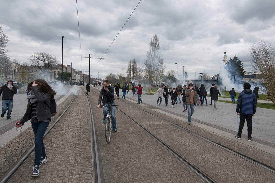 A cyclist protecting himself and ridding away from tear gas.