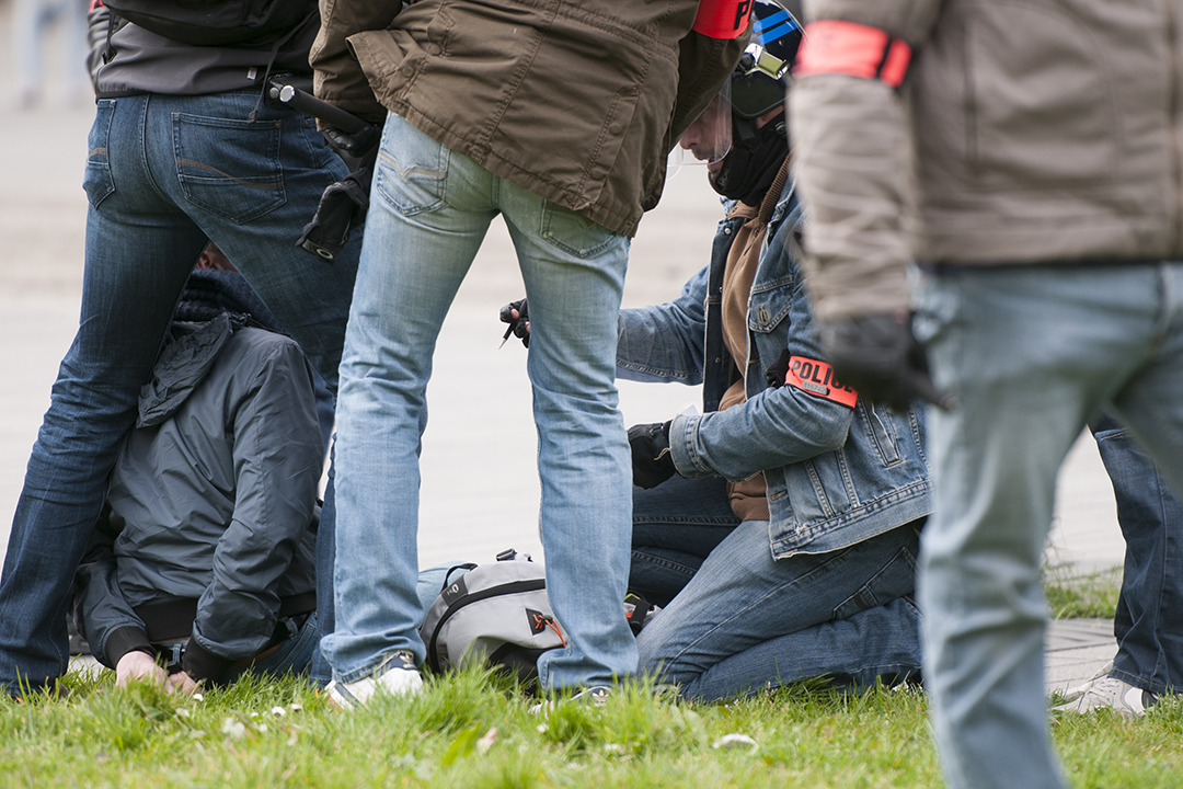 Police officer taking the identity of a protester shortly after arresting him.